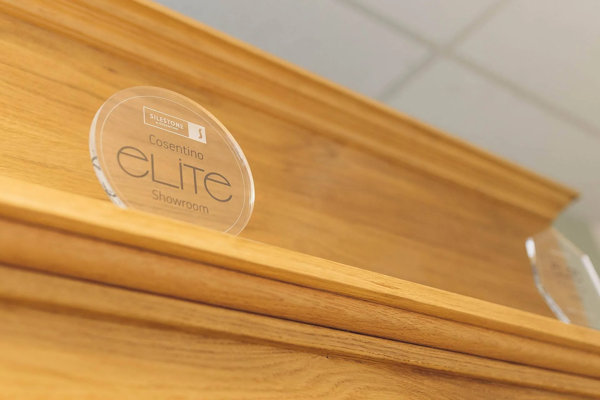 A clear circular sign on a wooden surface reads "Silestone by Cosentino," "Cosentino Elite Showroom."