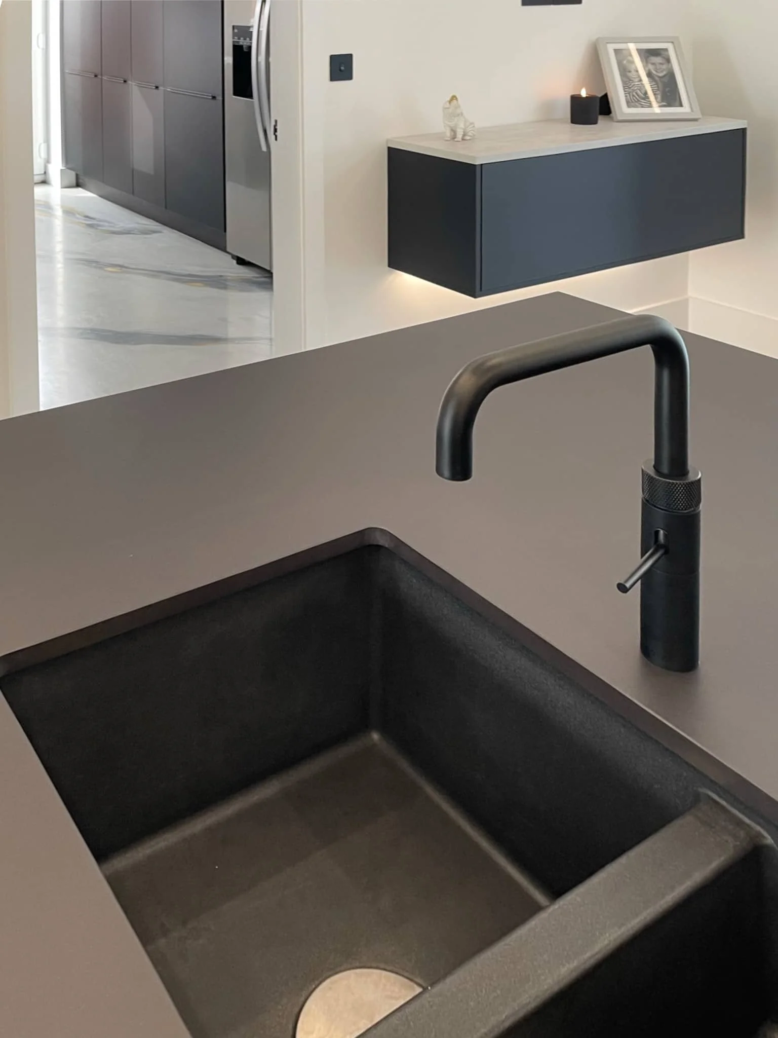 Close-up of a kitchen sink with a black faucet on a gray countertop.