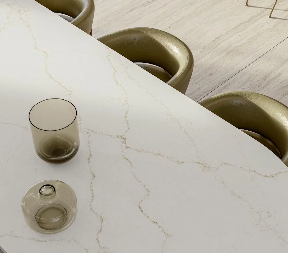 A white marble table with gold veining, three green upholstered chairs, and two empty glasses on the table.