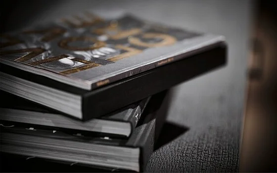 Stack of magazines on a dark table surface.