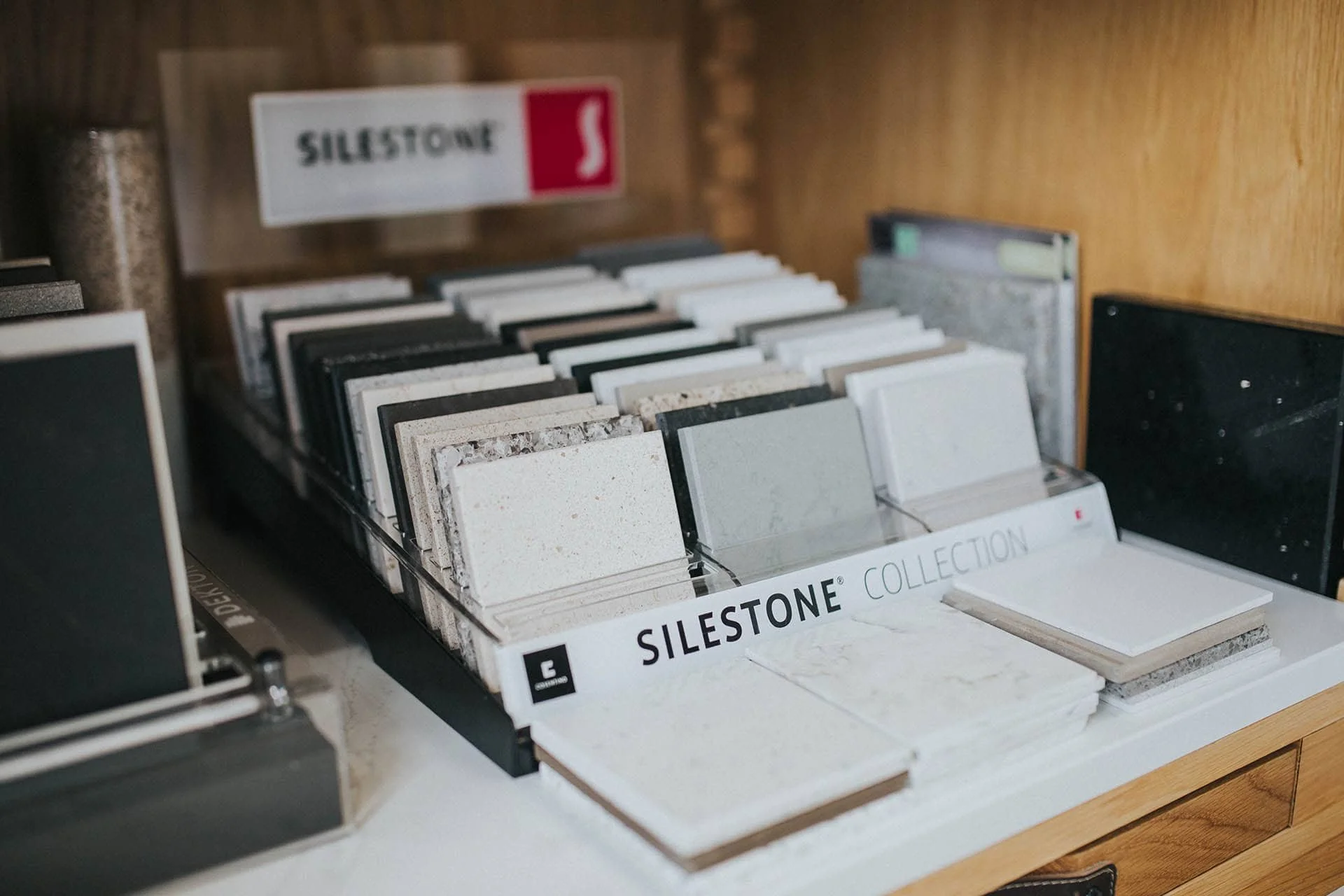 Display of various sample tiles from the Silestone collection, organized in clear sections with a sign labeled 'SILestone' in the background.