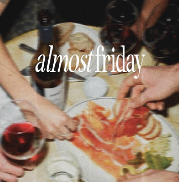 People preparing and sharing food and drinks, with glasses of red wine on the table and a plate of sliced tomatoes and greens, celebrating near Friday.