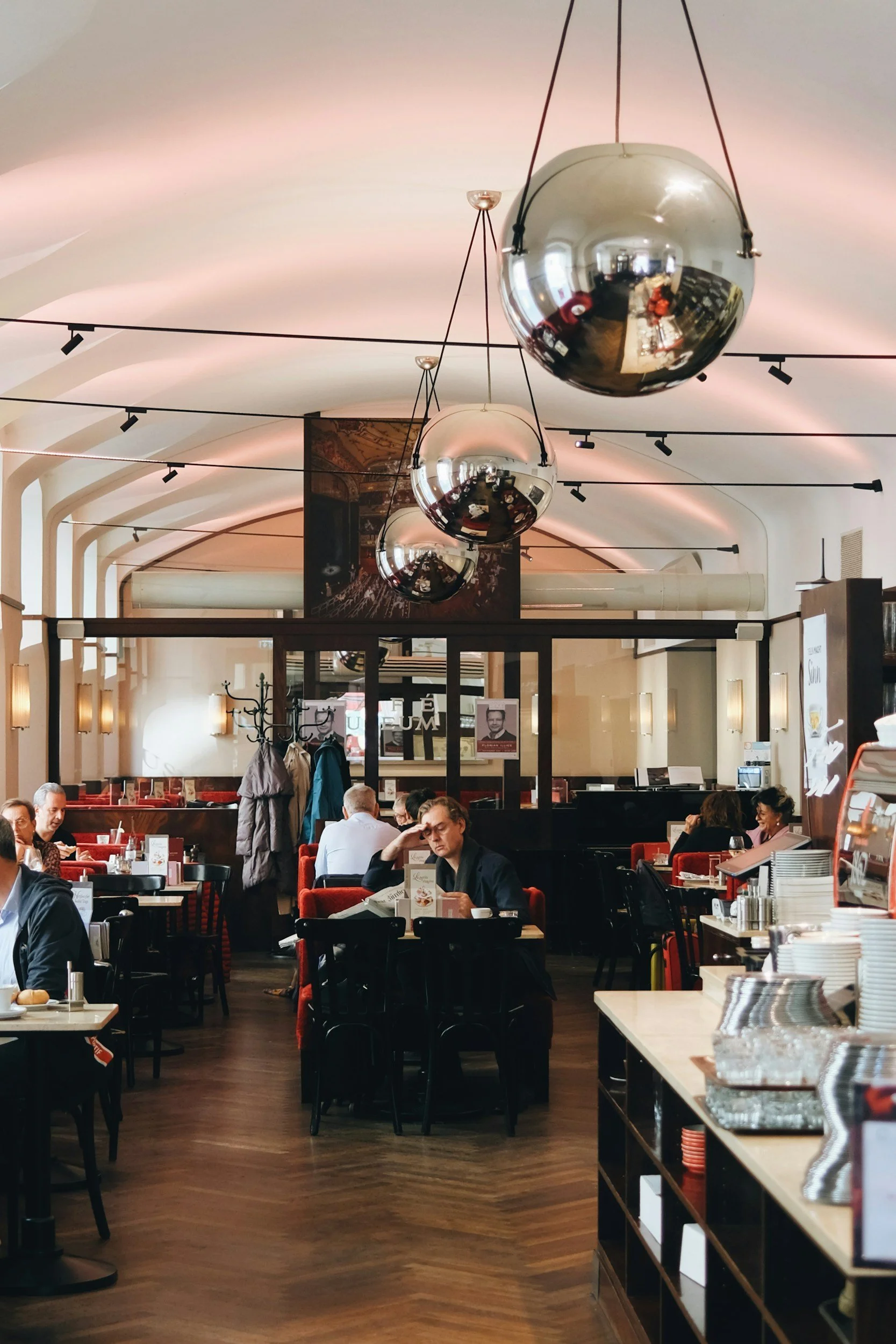 Interior of a restaurant with patrons seated at tables, large round mirror balls hanging from the ceiling, and warm lighting.