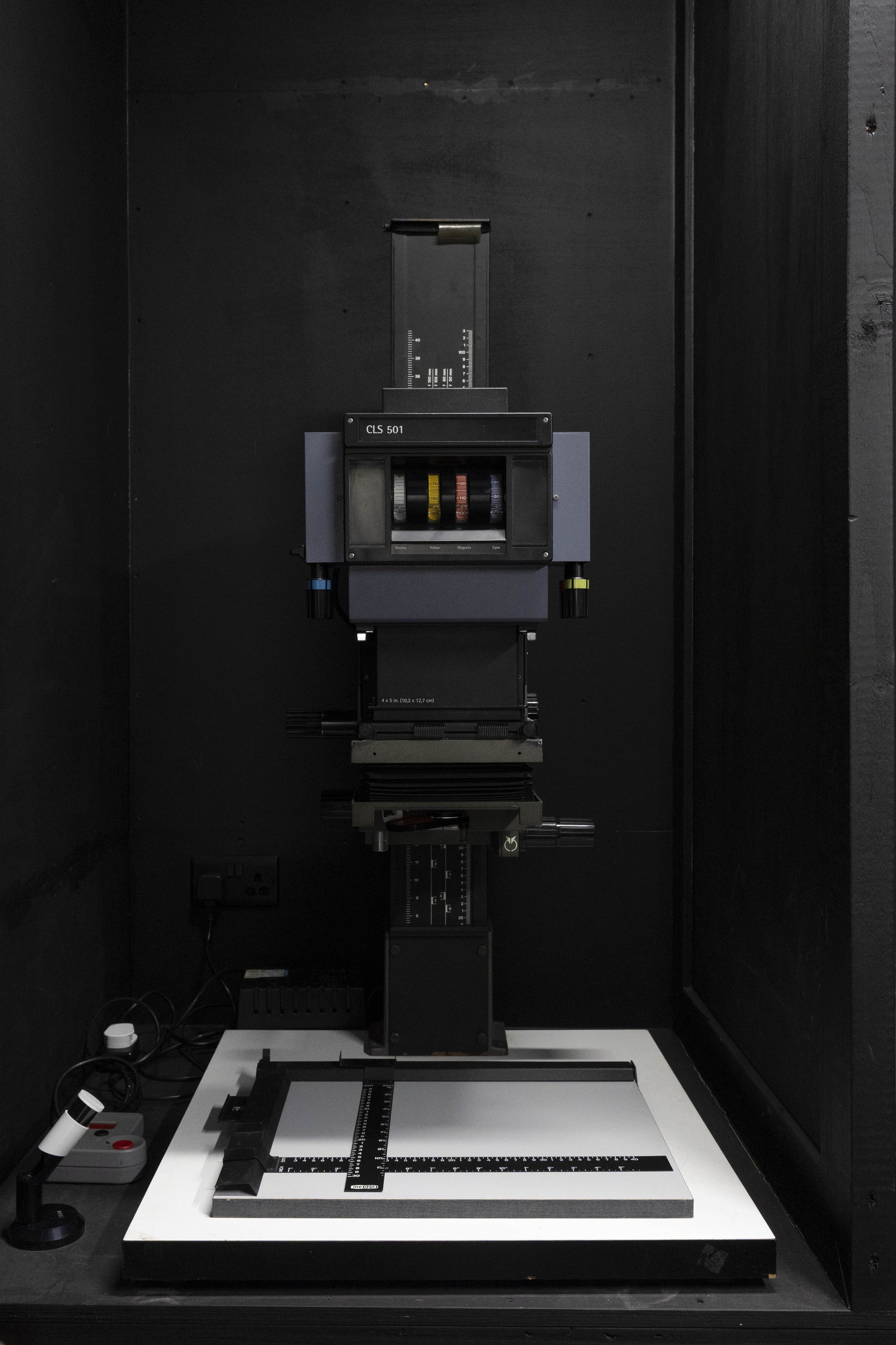 A scientific instrument setup with a black background, featuring a motion stage, a ruler, and measurement scales on a white platform, used for precise measurements or experiments.