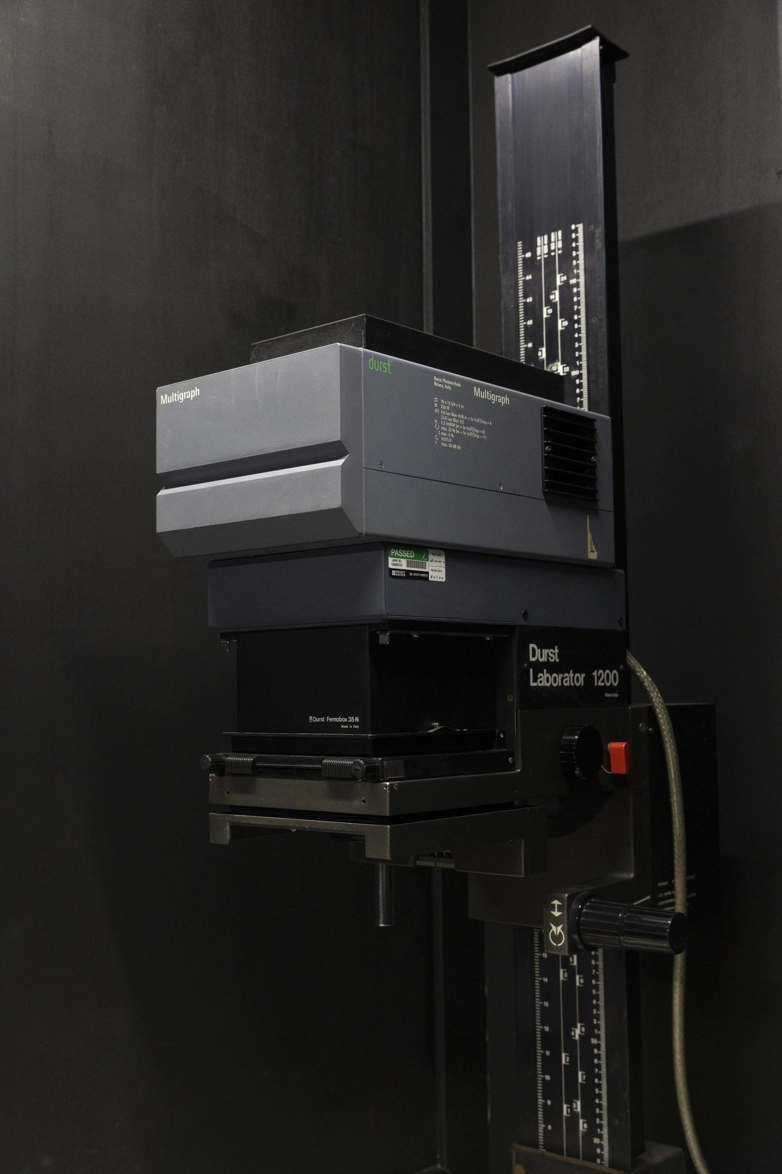 A scientific device, labeled 'Durst Laboratory 1200', mounted on a black stand against a dark background.