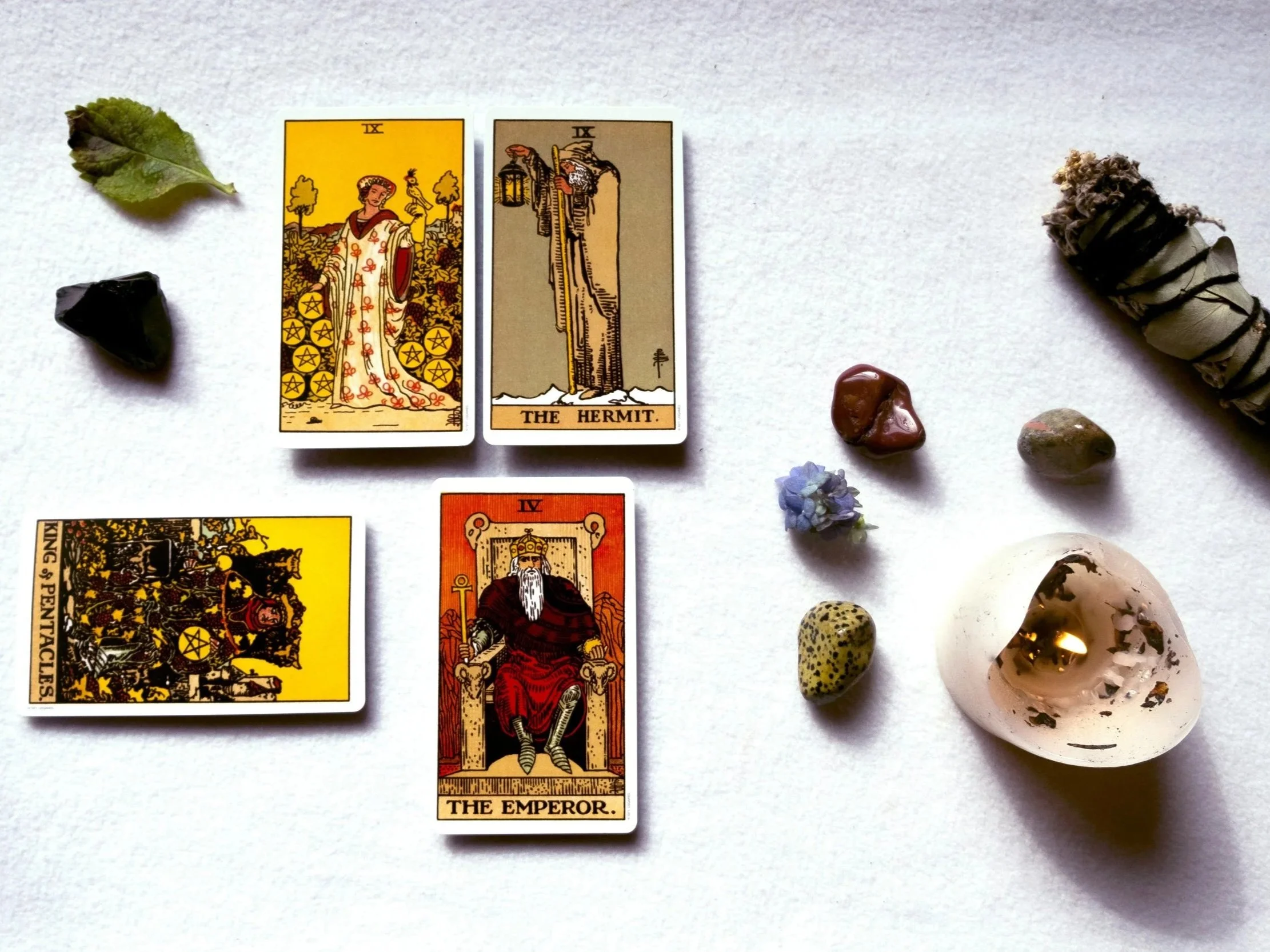 Tarot con cuatro cartas, hojas, piedras y un objeto de cerámica