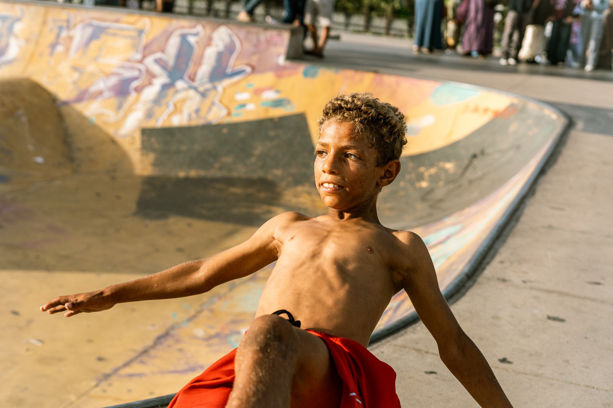 Teenage boy skateboarding in a colorful graffiti-covered skate park bowl