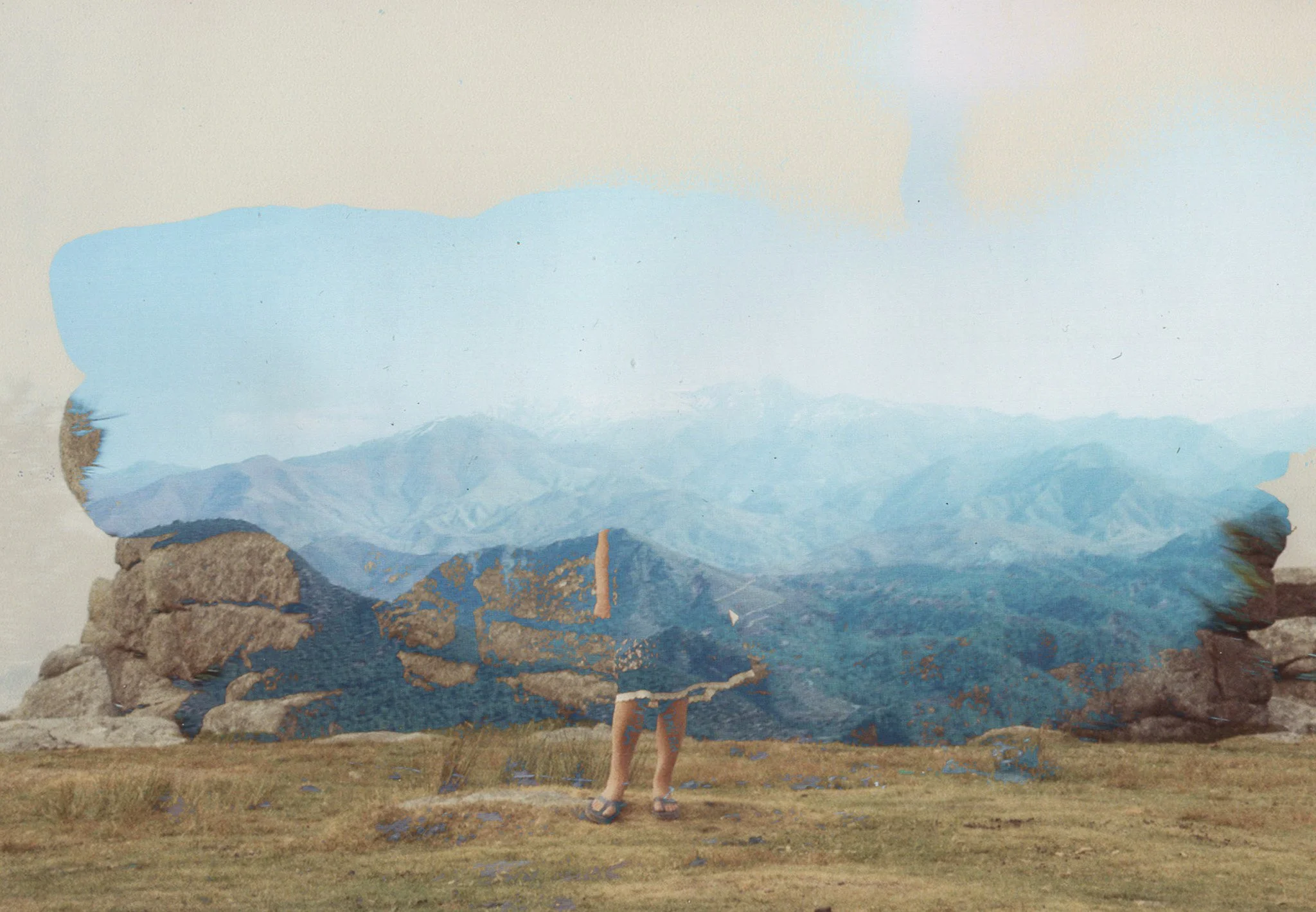 Person standing in front of a large landscape painting on an outdoor wall, wearing shorts and sandals, with legs shown.