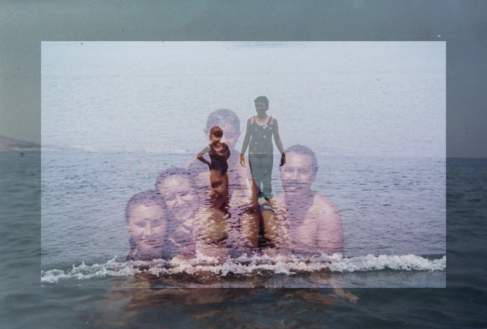 A double exposure photo of a group of people at the beach, showing their faces overlapped and blending with the ocean and sky in the background.
