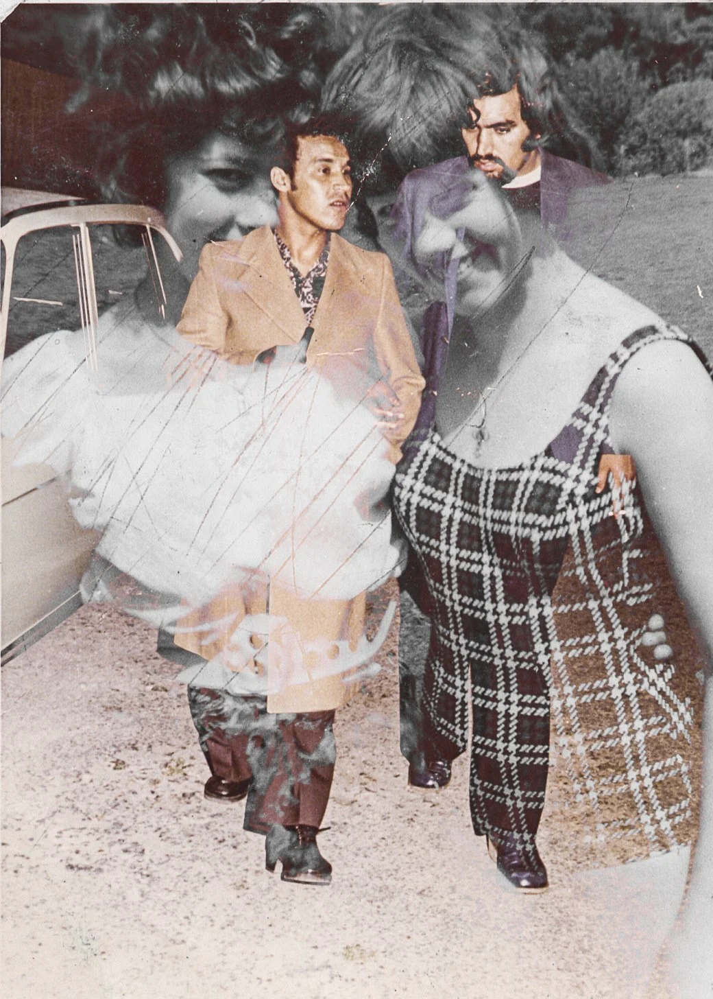 A double exposure photograph featuring two men and two women. The men are dressed in vintage clothing, walking outdoors near a car, with grass and trees in the background. The women are superimposed, with one smiling and the other looking down, both 