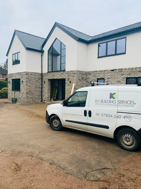 New house under construction with a KV Building Services company van parked in front.