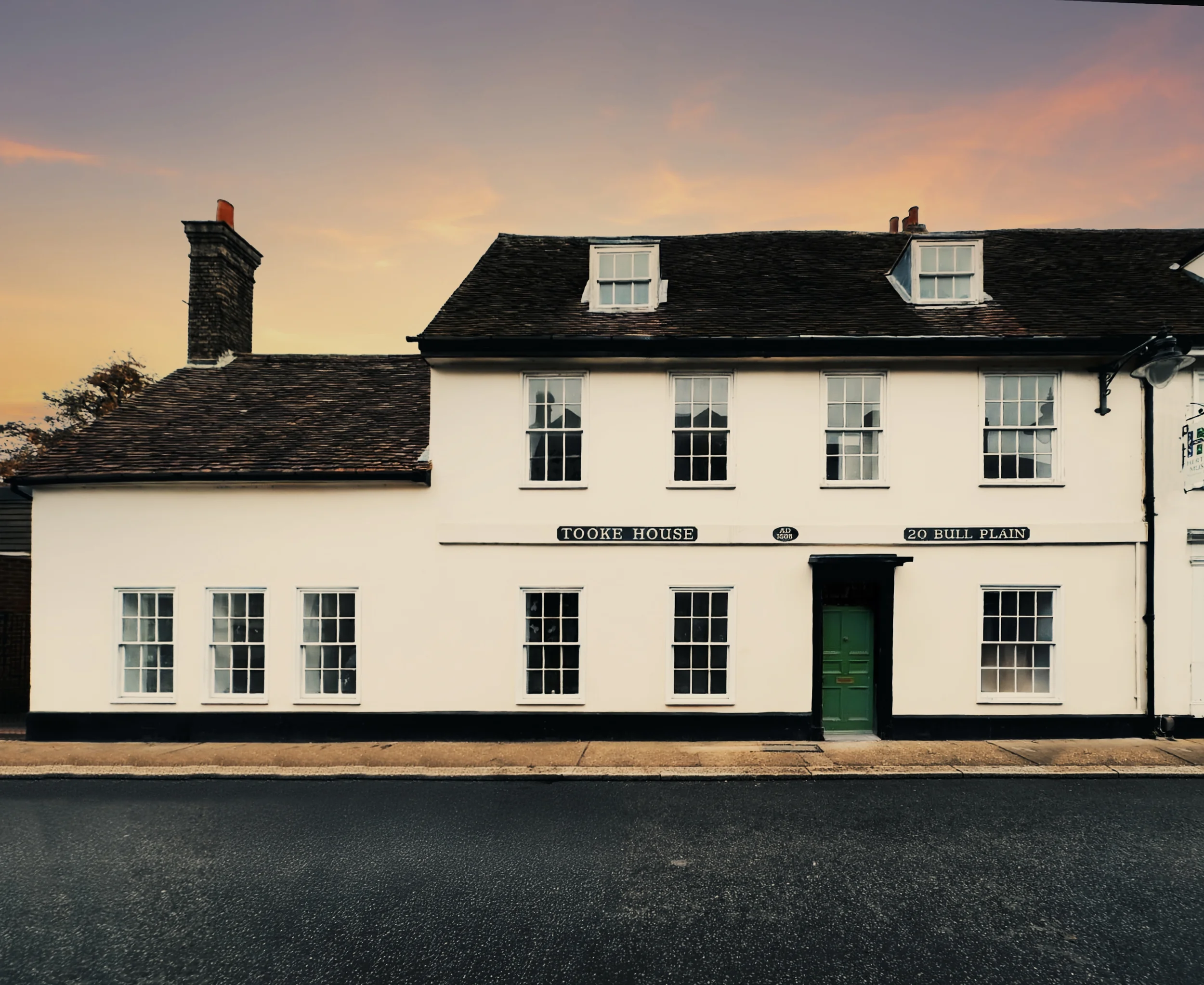 White building with a green door and multiple windows, a sign reading 'Tooke House' on the front, and a clear sky at sunset.
