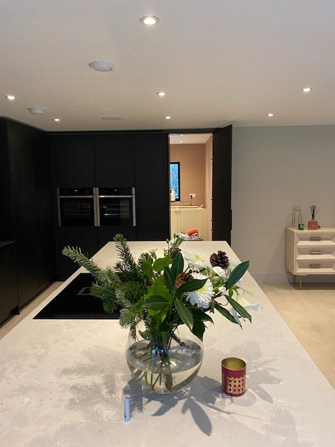 A modern kitchen with a white island, a vase with flowers and greenery, and a small candle on the countertop.