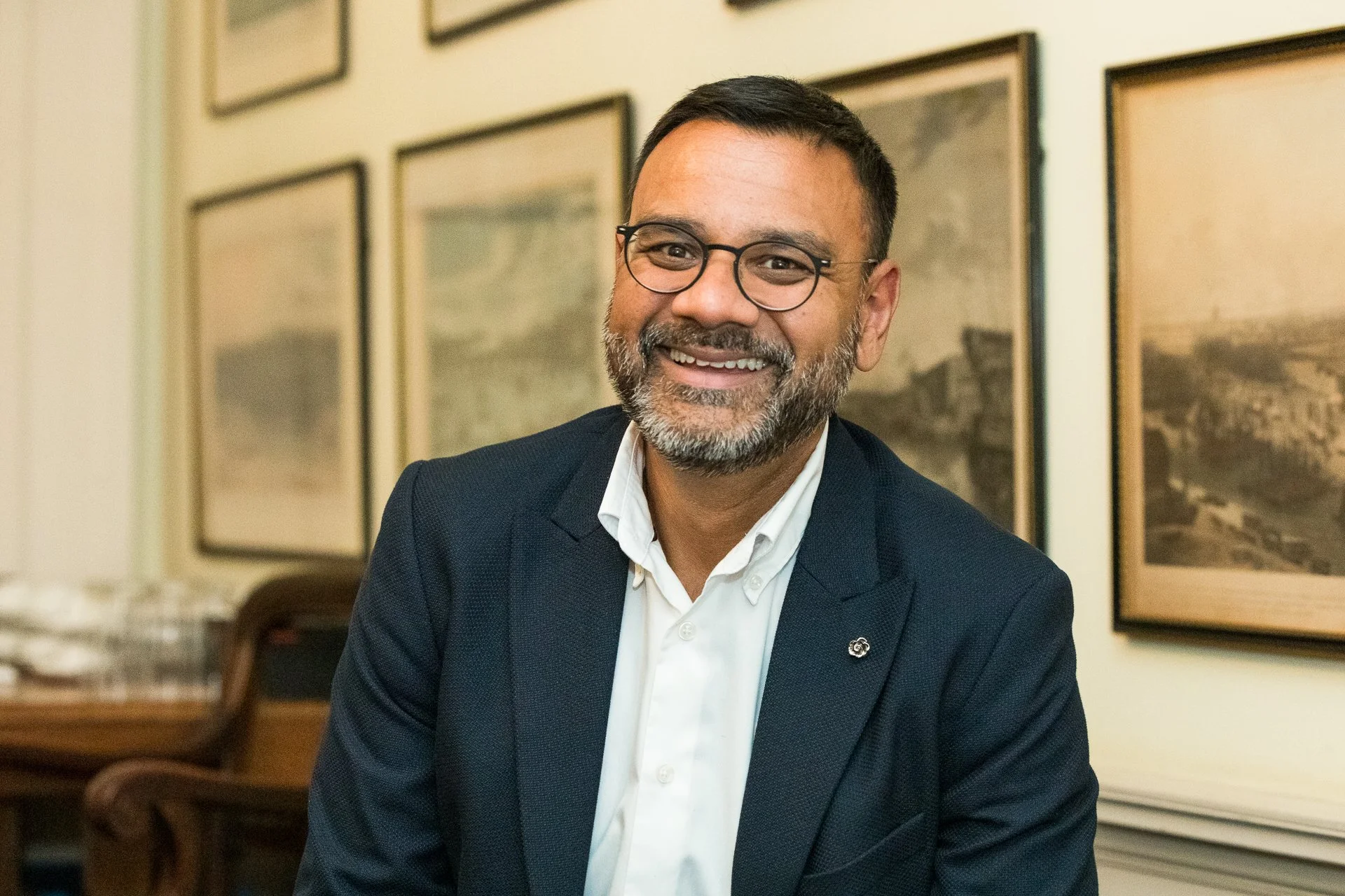 Colour portrait of a smiling man with glasses, a beard, and short hair