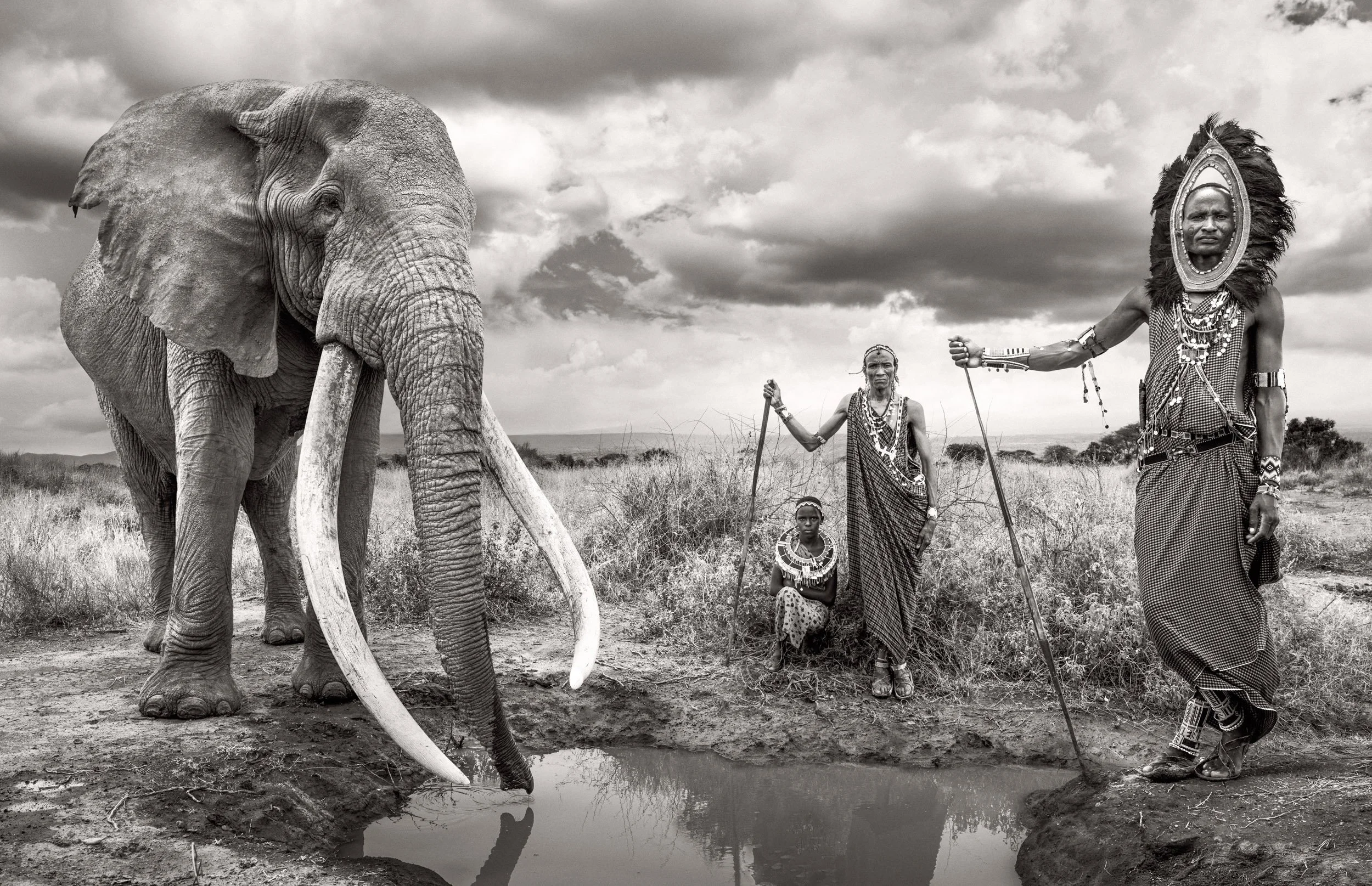 In this composite, Maasai people stand beside Craig, the giant tusker elephant of Amboseli National Park, set on the open plains of southern Kenya.