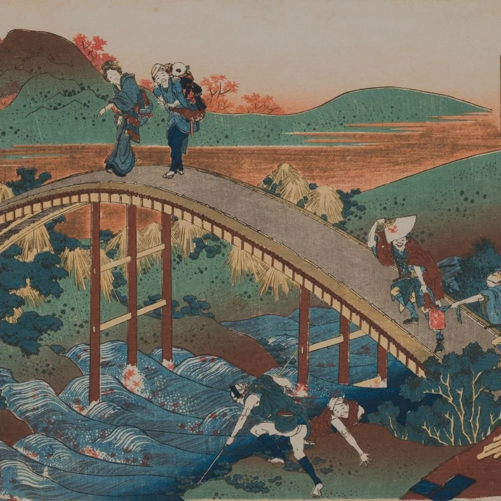 A traditional Japanese woodblock print depicting people crossing a bridge over a river, with mountains, trees, and houses in the background.