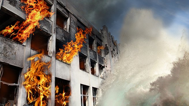 Un immeuble en feu avec des flammes et de la fumée intense.