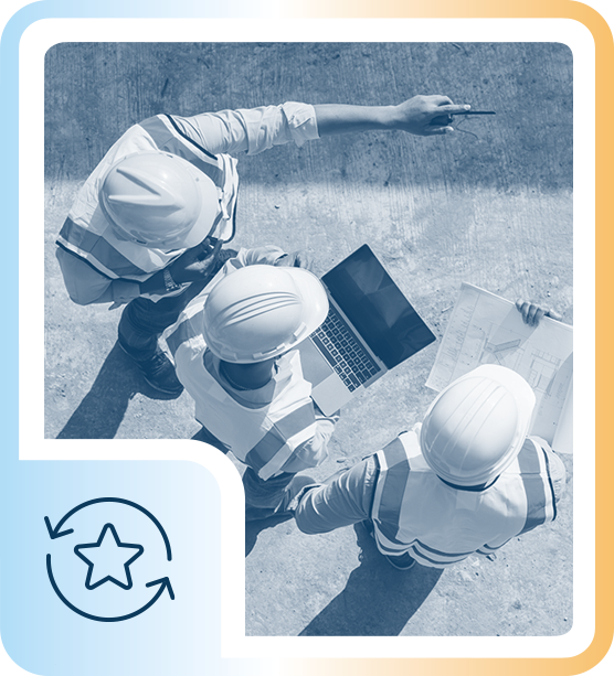 Three construction workers wearing safety helmets review plans and a laptop on a construction site.