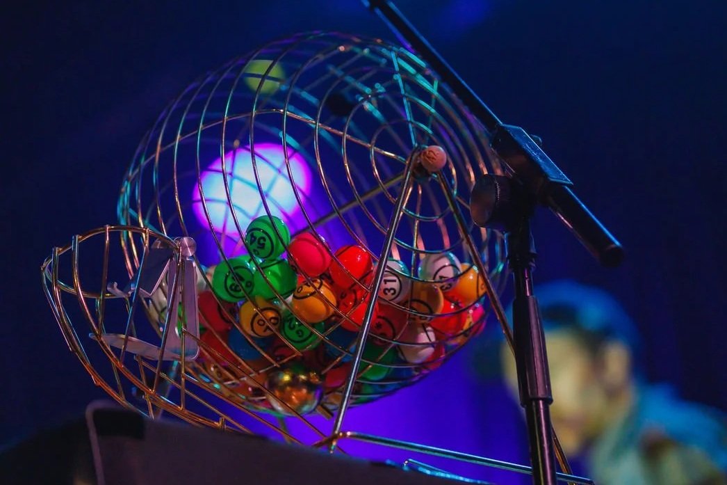 A bingo cage filled with colorful bingo balls and a bingo caller machine against a dark background.