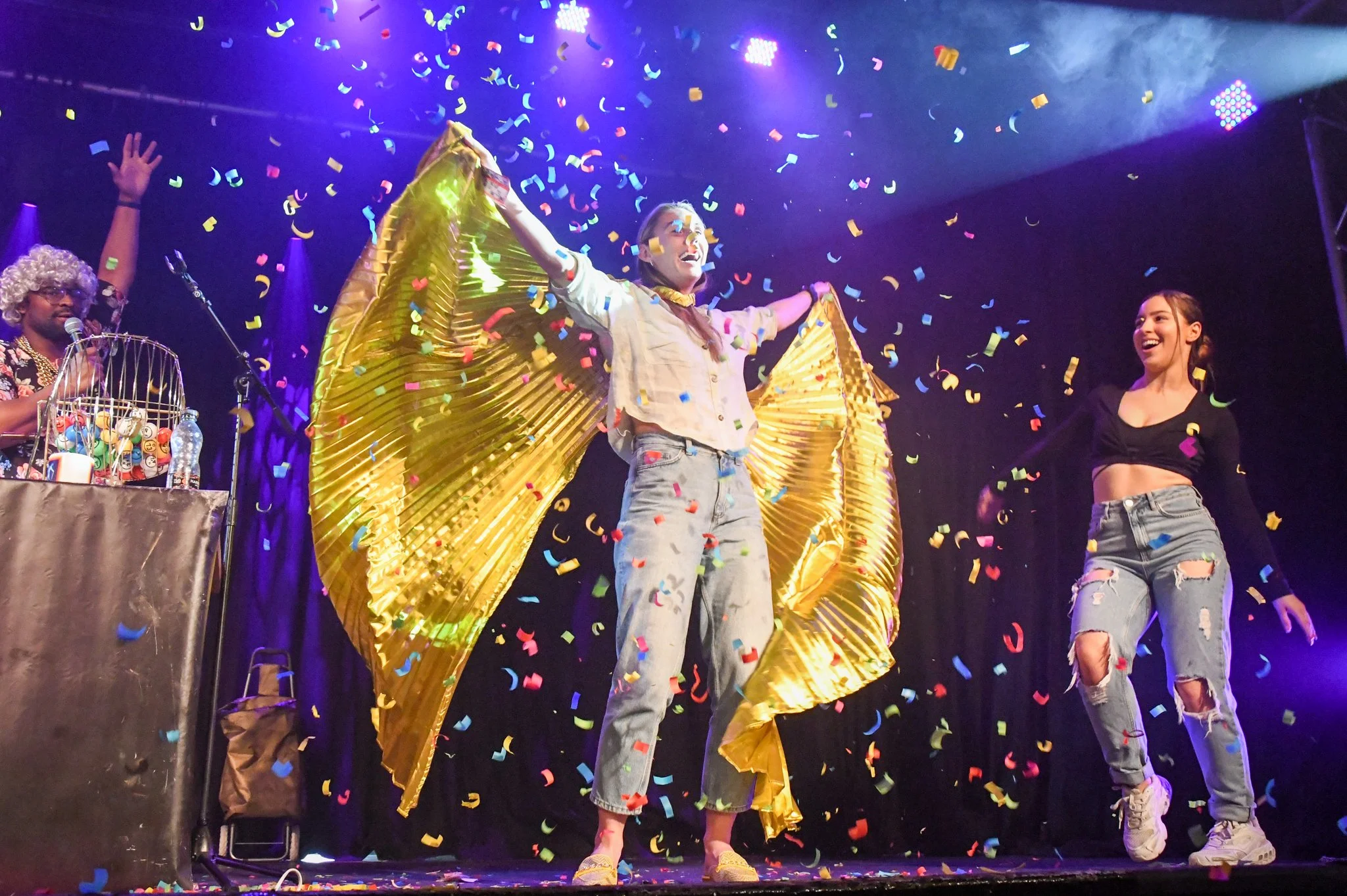 A lively scene at Blingo Bingo night with three people celebrating amid colourful confetti falling from above.