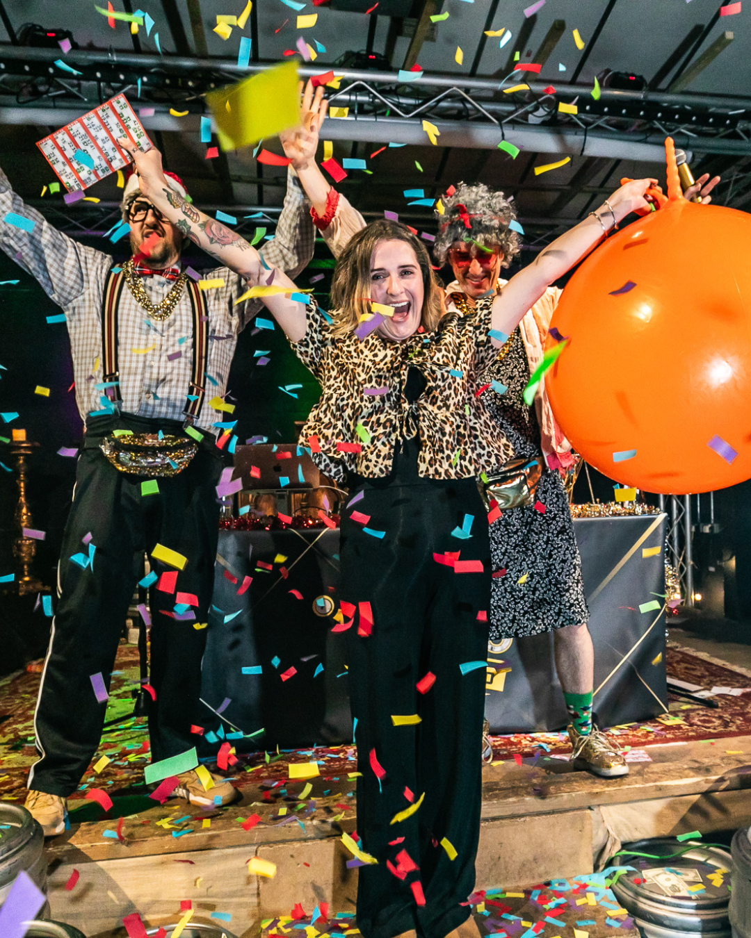 People celebrating winning bingo with colourful confetti, a large orange pumpkin, and a festive atmosphere.