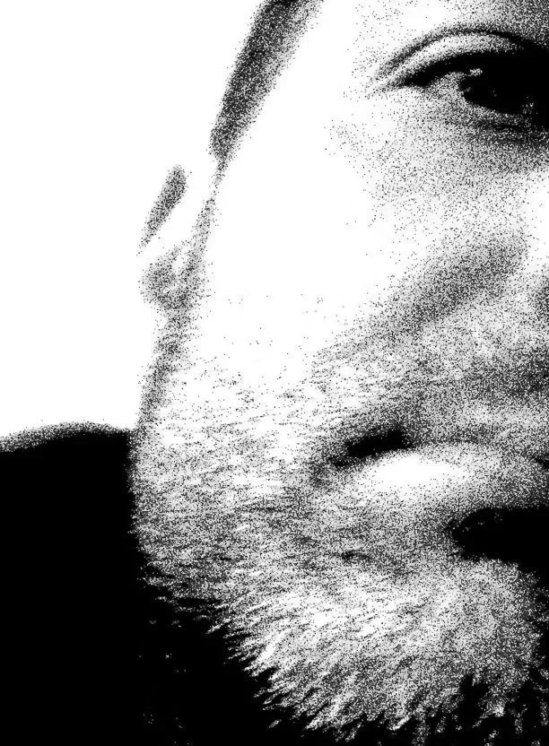 Close-up, black-and-white pixelated image of a man's face, showing part of his right eye, nose, and beard.
