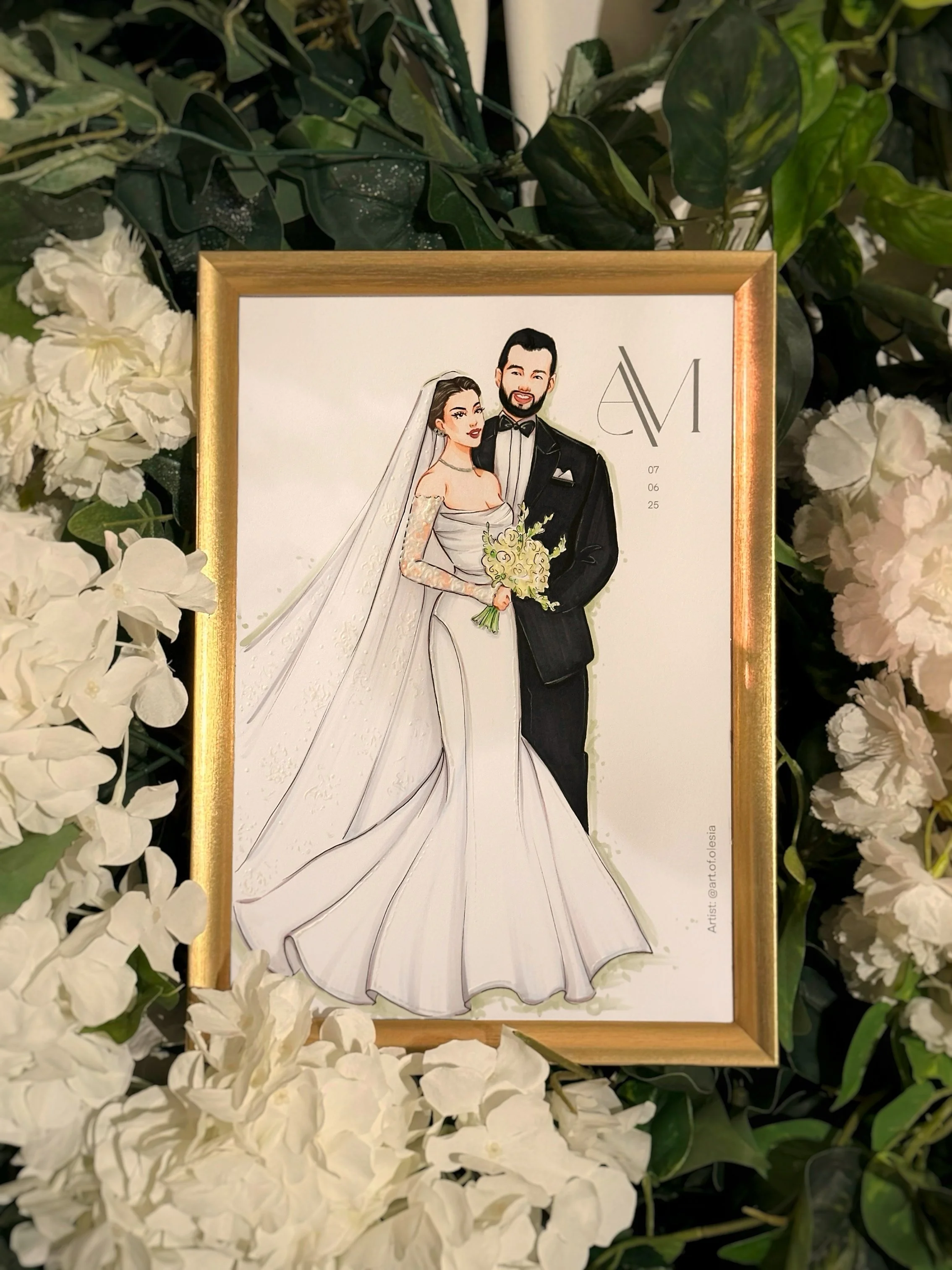 A framed illustrated portrait of a bride and groom surrounded by white flowers and green foliage