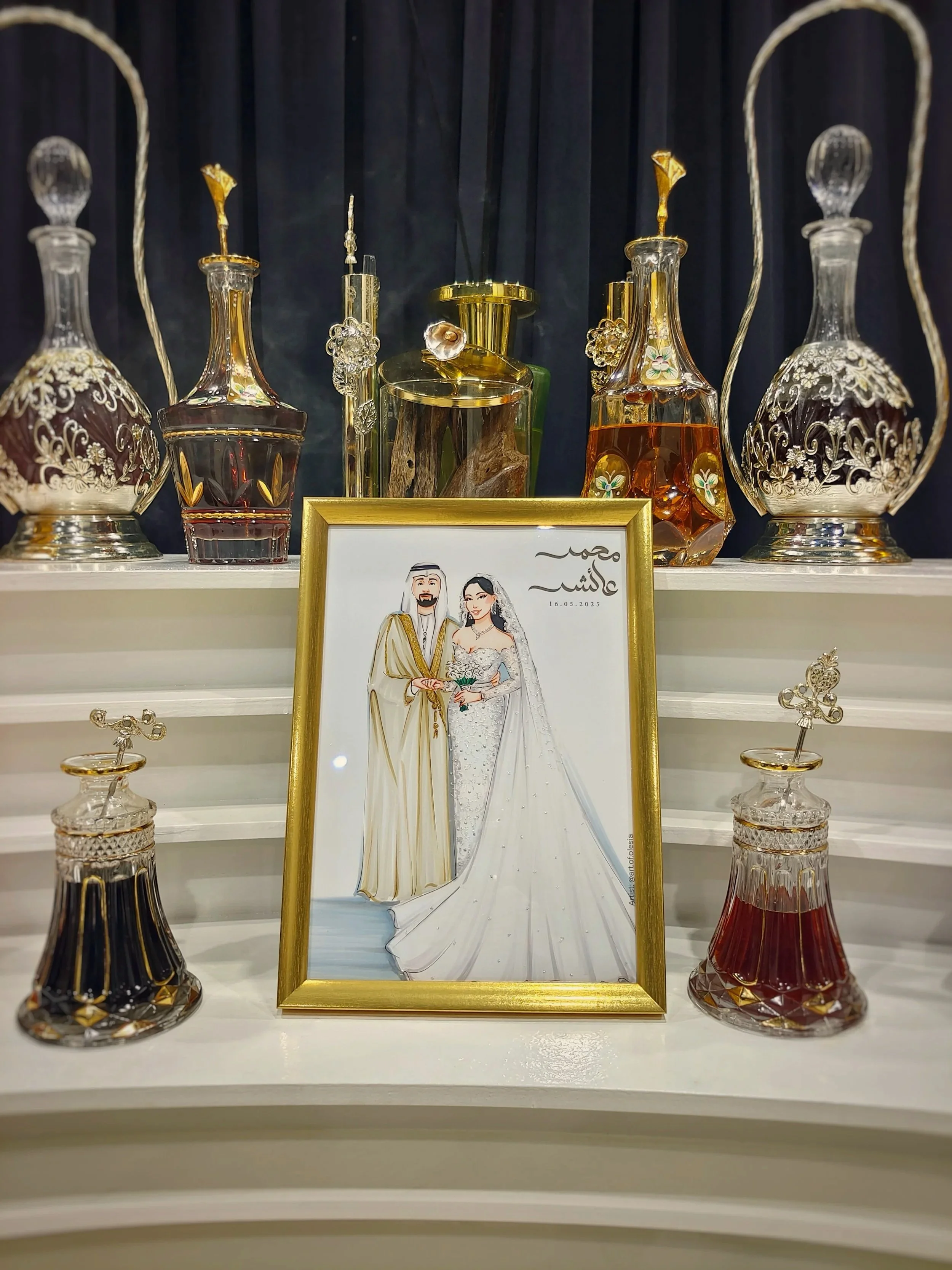 Decorative glass bottles and a framed artwork of a bride and groom, with a dark curtain background.