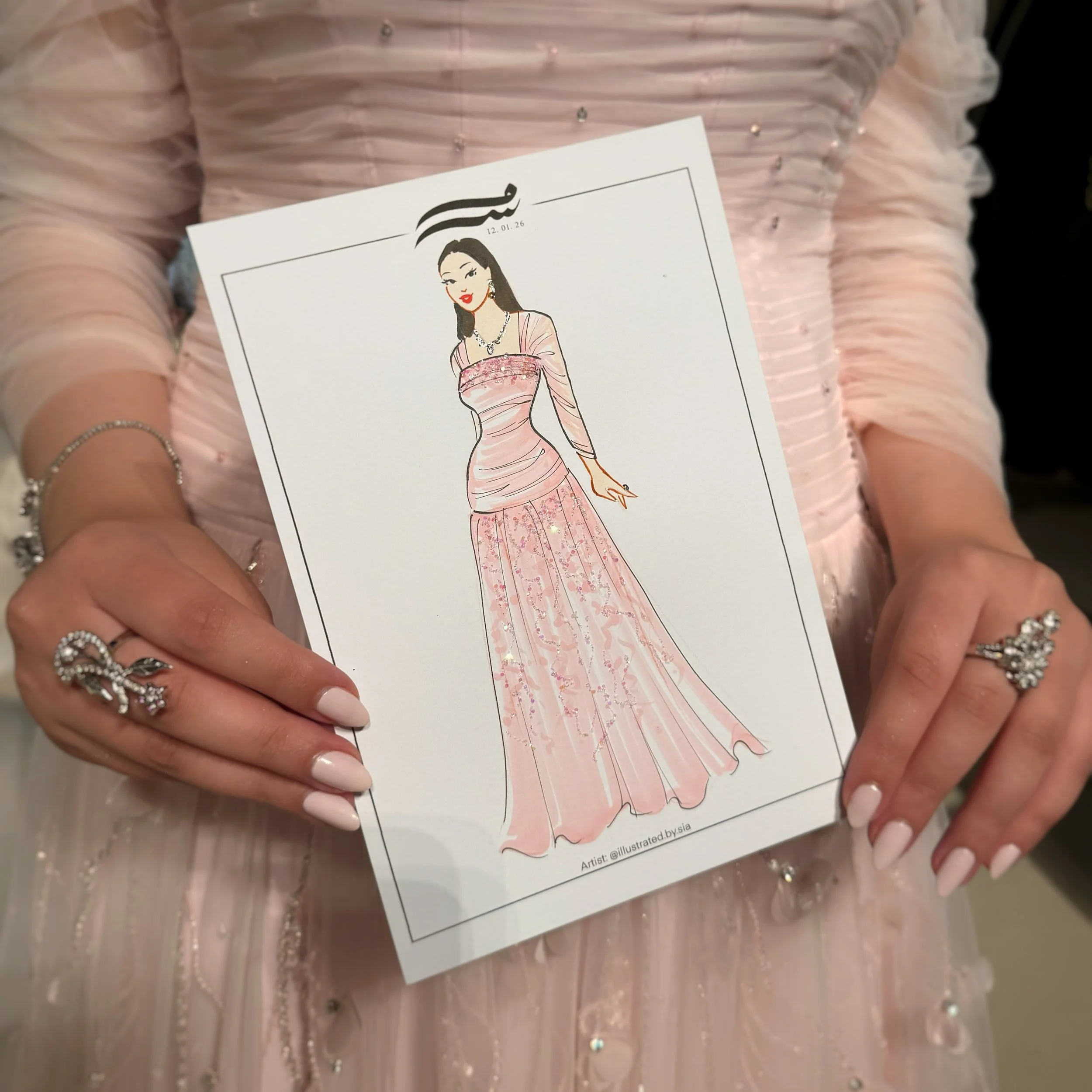 Close-up of a woman holding a paper with a fashion illustration sketch