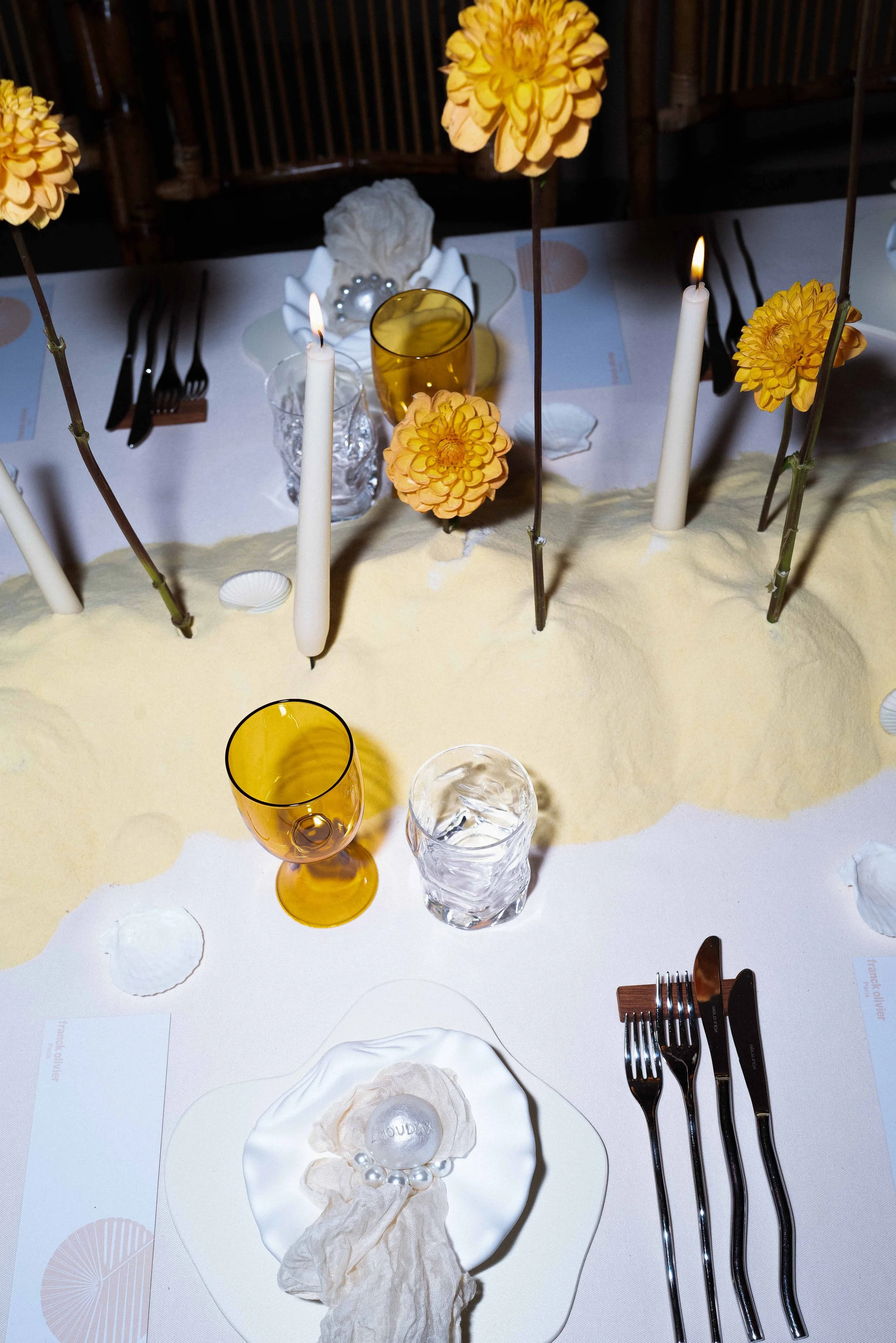 Table setting with a yellow centerpiece, candles, floral decorations, and glassware.