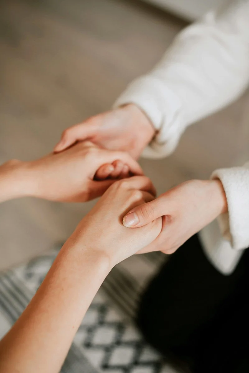 A supportive doctor holds hands with a patient during Exposure Response Prevention therapy in a close-up shot.