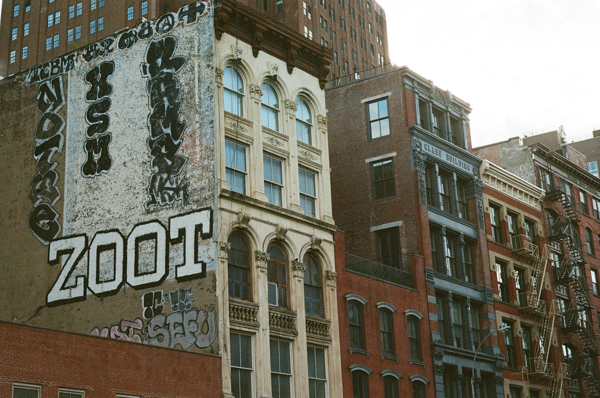 City buildings with graffiti on the side of one building, showing the words 'Zoo' and various street art.