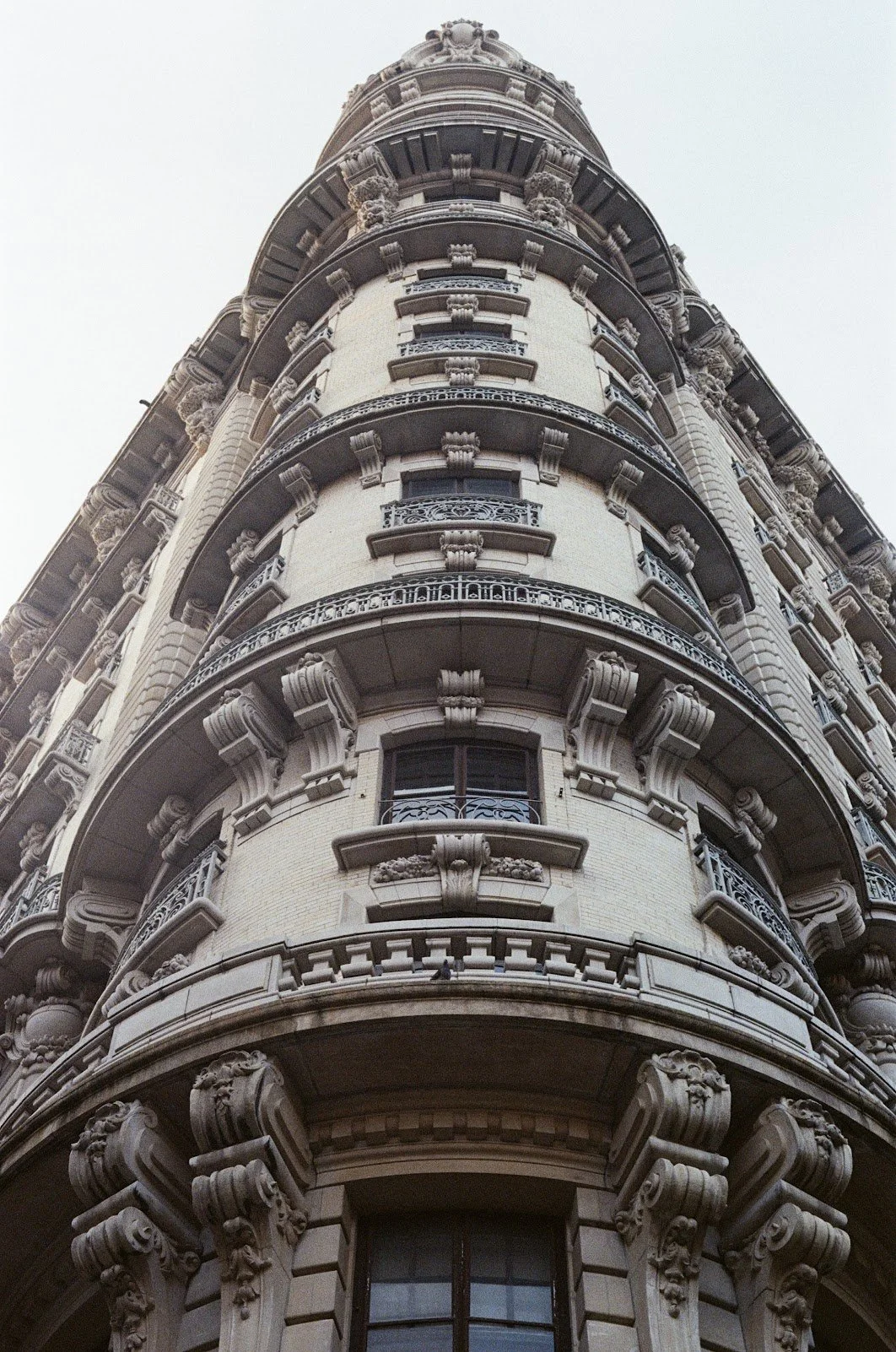 Upward view of a historic European-style building with ornate stone carvings and wrought iron balconies.