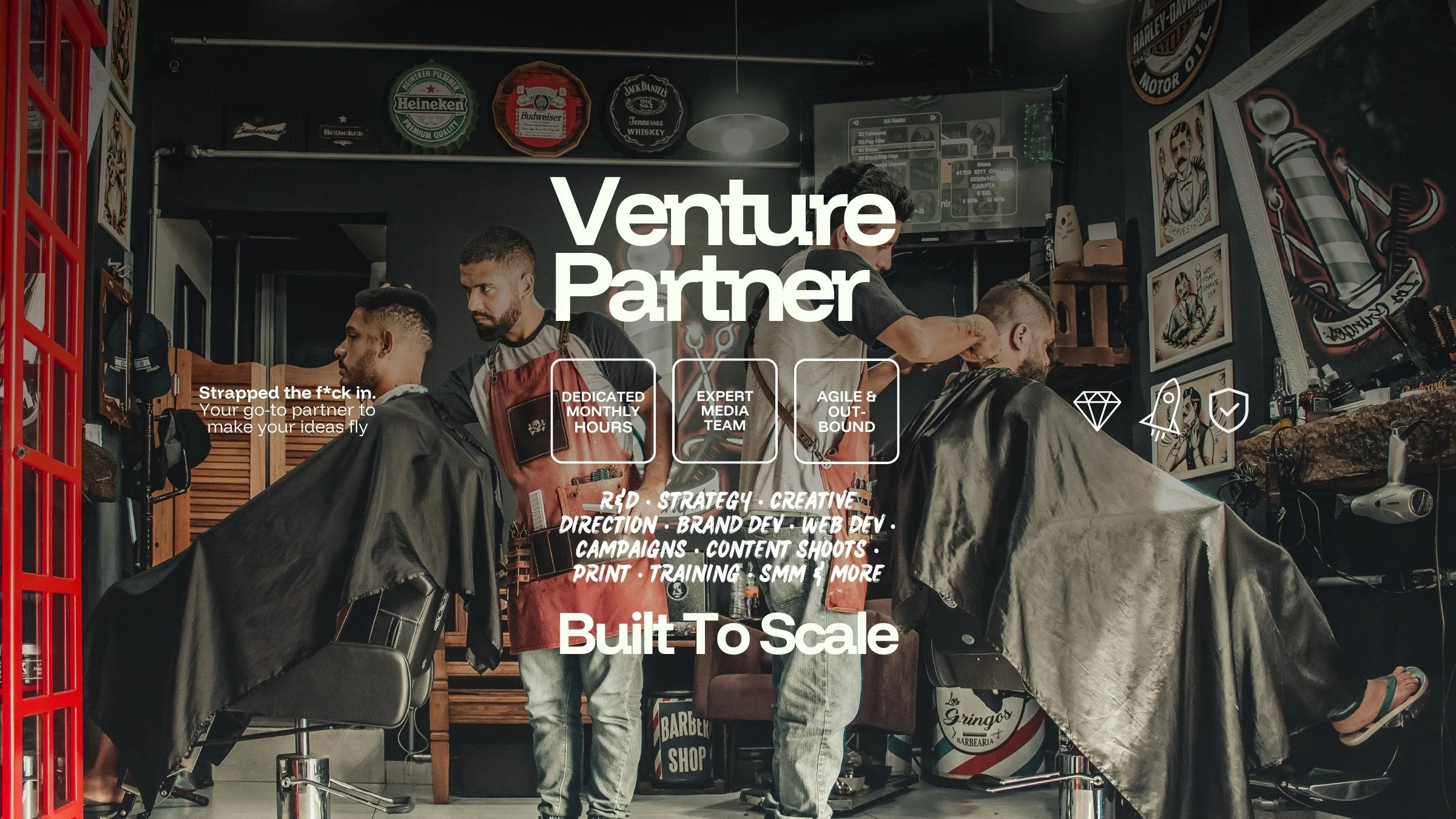 An image of a busy barbershop, with 2 barbers and 2 men getting their hair cut, a modern cool looking aesthetic, taken with a professional camera and lighting - with text overlayed promoting venture partnership services from Made by UNO, a company ba
