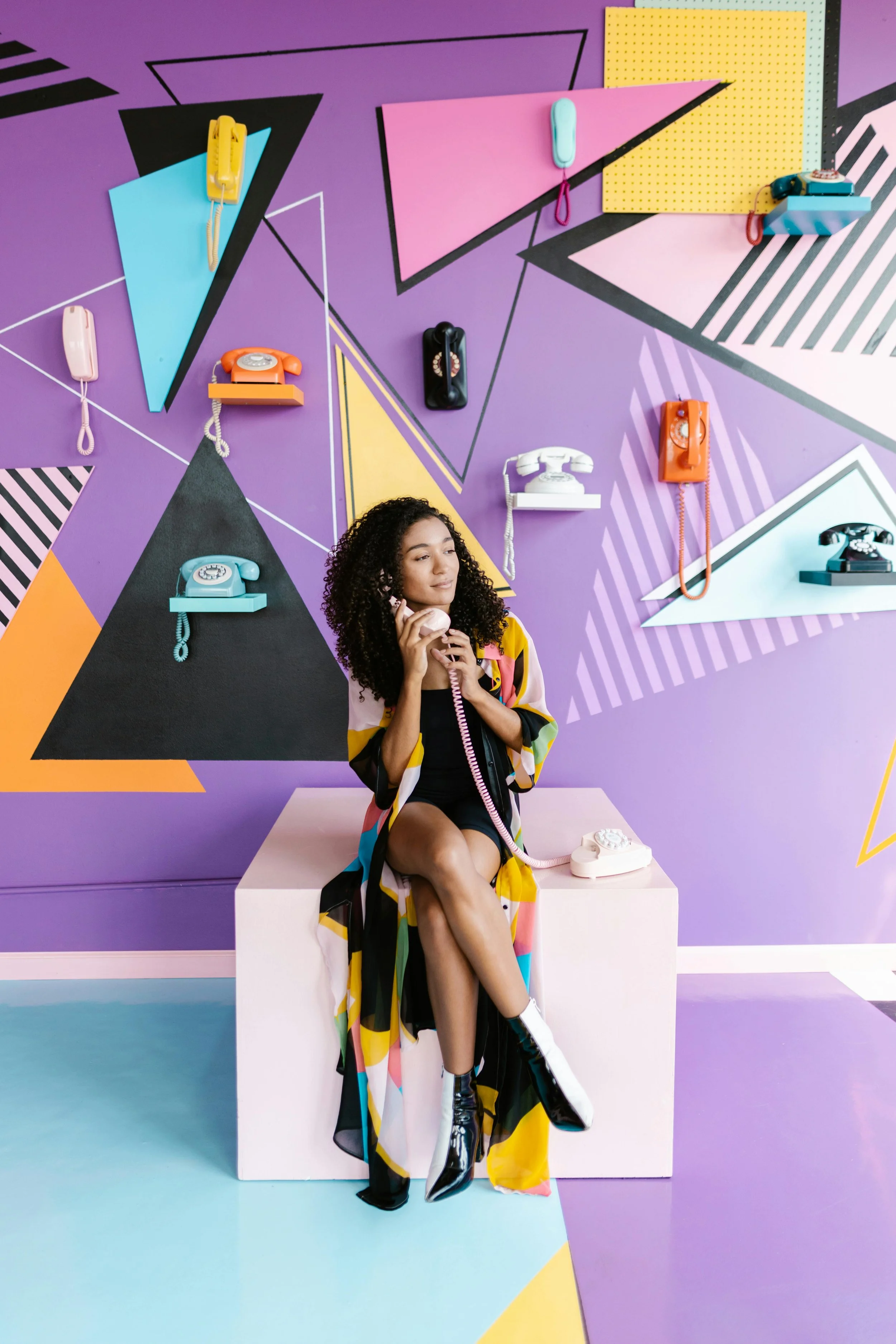 image of a young woman in a brightly coloured room, holding a telephone and smiling, shot in a professional video studio with the words "made by uno -  brand services in doncaster" overlayed over the top