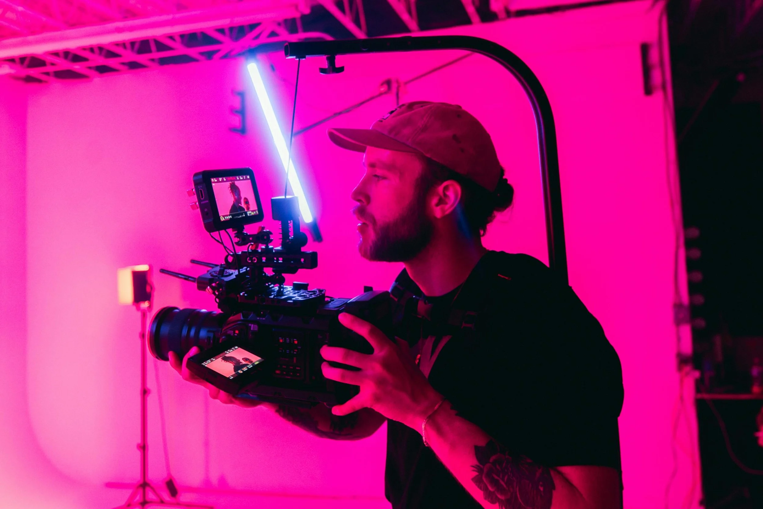 Man holding a professional film camera on a photoshoot in doncaster, wearing a tshirt with the words "made by uno - brand and video studio in doncaster & manchester" visible on his tshirt