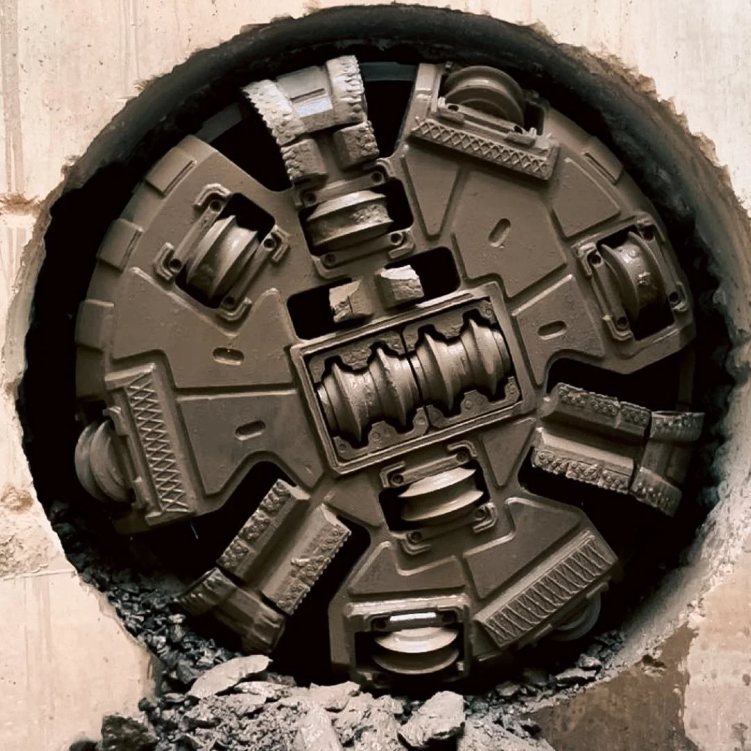 Cross-section of underground tunnel with large, circular concrete structure and machinery components inside, with a professional videographer partially visible in the shot.