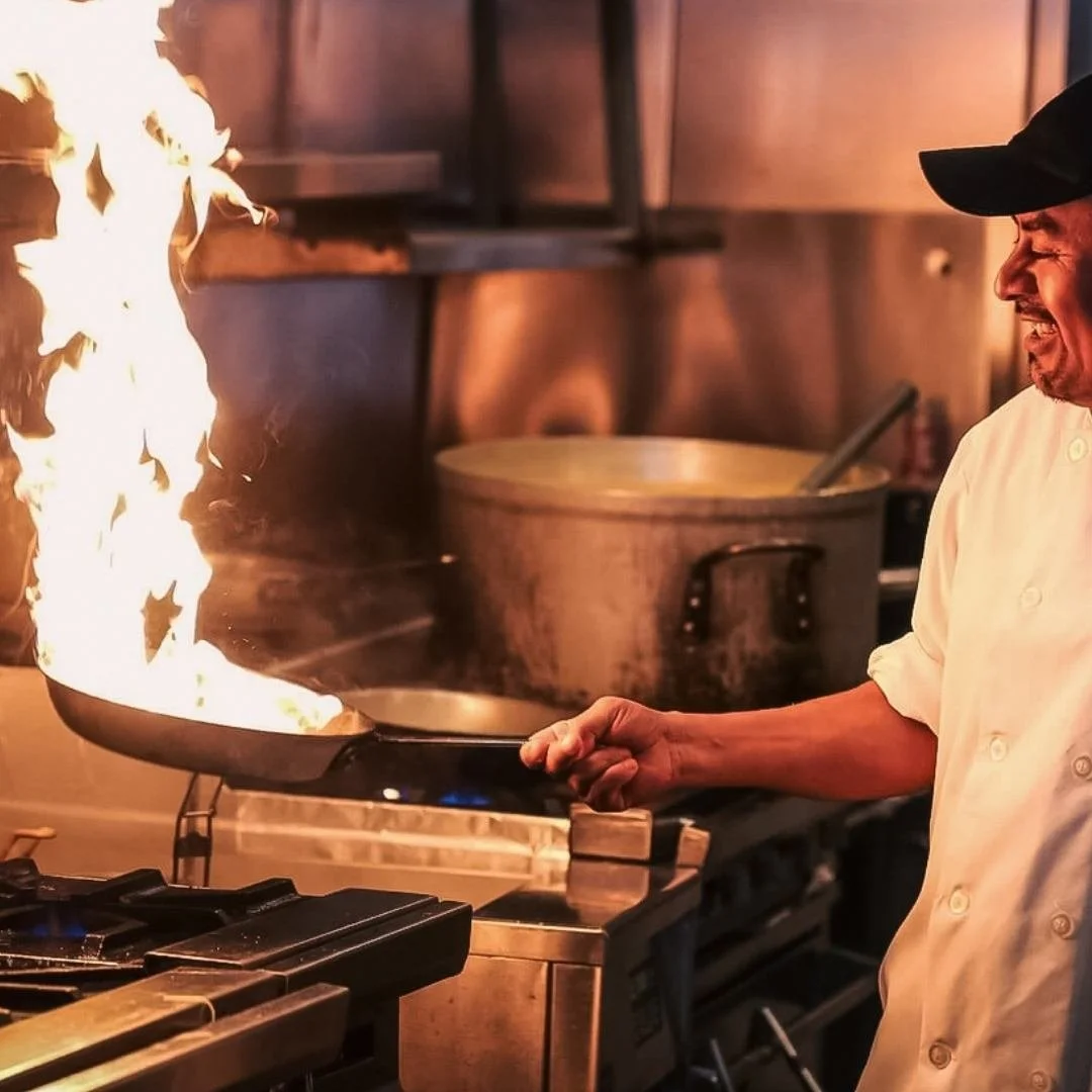 Chef cooking on a stove with flames rising from a pan in a professional kitchen in Doncaster