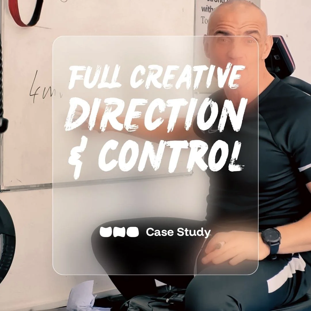 Man in black athletic wear sitting on with whiteboard and gym equipment in background, overlaid text reading 'Full Creative Direction & Control'.