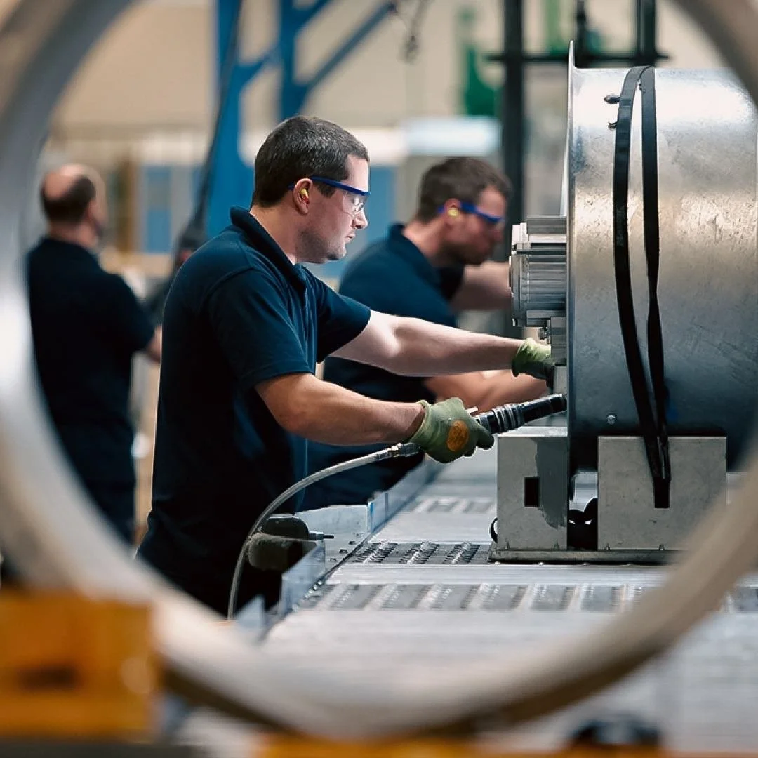 Three Polypipe workers in safety glasses and gloves operating machinery at an industrial manufacturing line in Doncaster.