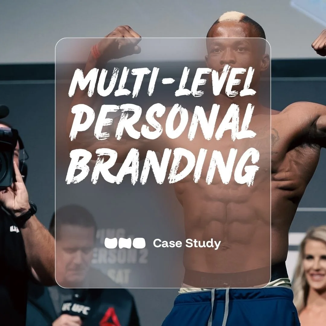 Marc Diakiese flexes his biceps on stage as he stands on the scales, with a photographer from UNO and other people watching in the background.