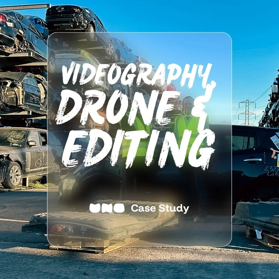 A drone shot of damaged and wrecked cars stacked on top of each other at Synetiq's Doncaster salvage yard, with a person wearing a yellow safety; text overlaid stating "videography, drone video & editing services by UNO"