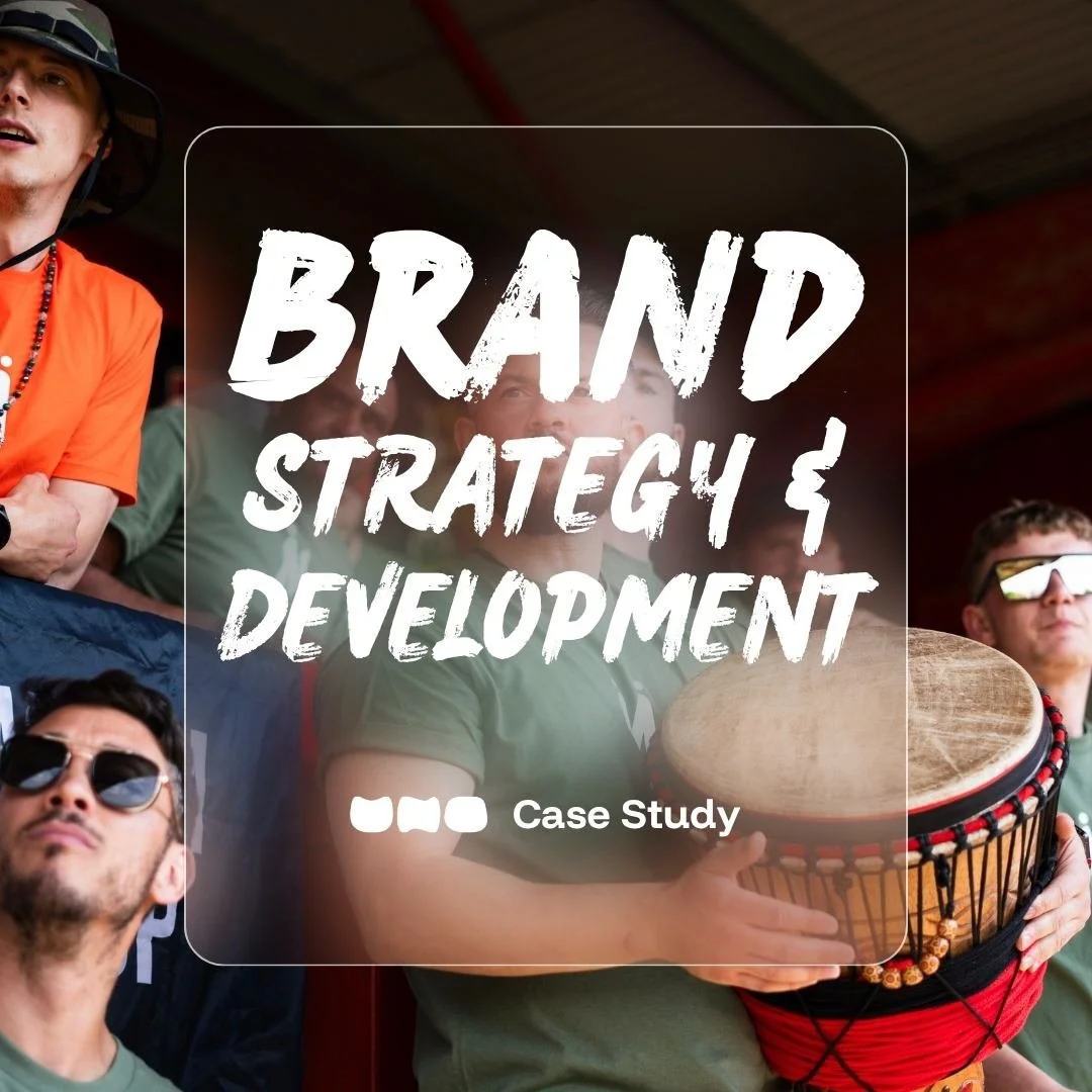 Group of men gathered at a football match wearing Mandem Meetup tshirts, with one person holding a traditional African drum, under a roof structure. Text overlaid stating "brand strategy & brand development by UNO"