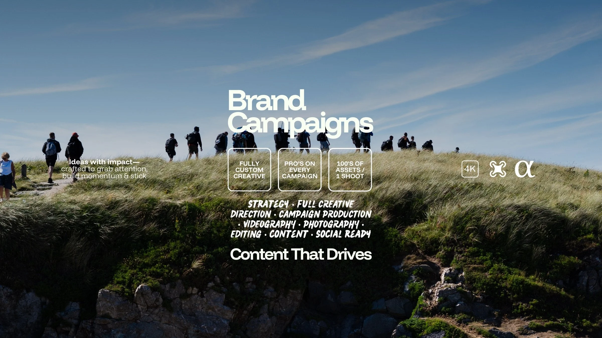 A image from a cinematic brand campaign of people walking in the countryside on a sunny day - with text overlayed promoting campaign production & branding services