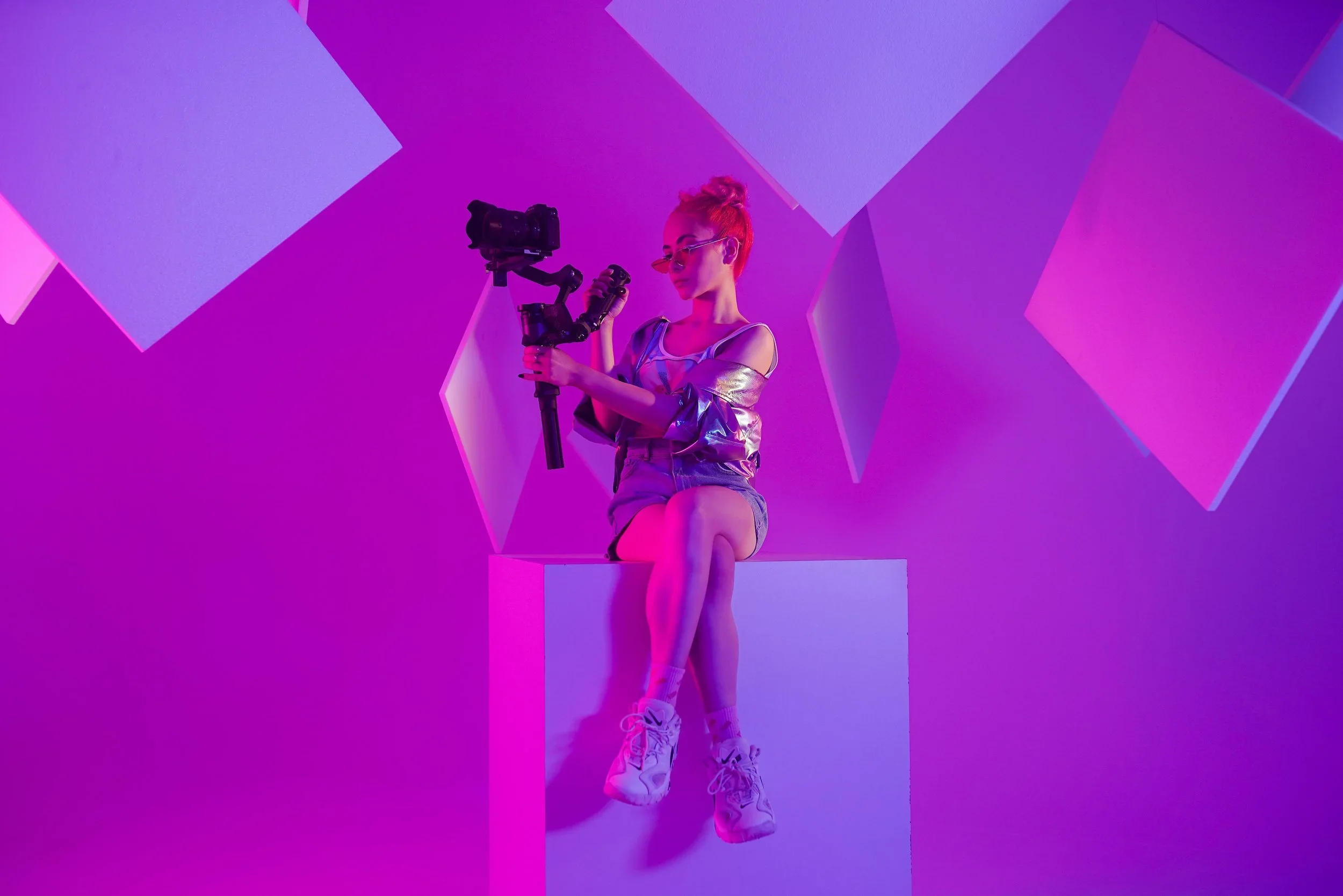 A professionally shot image of a woman holding a DSLR camera mounted on a gimble - as part of a professional brand campaign shoot with cinema cameras and lighting, in a professional studio