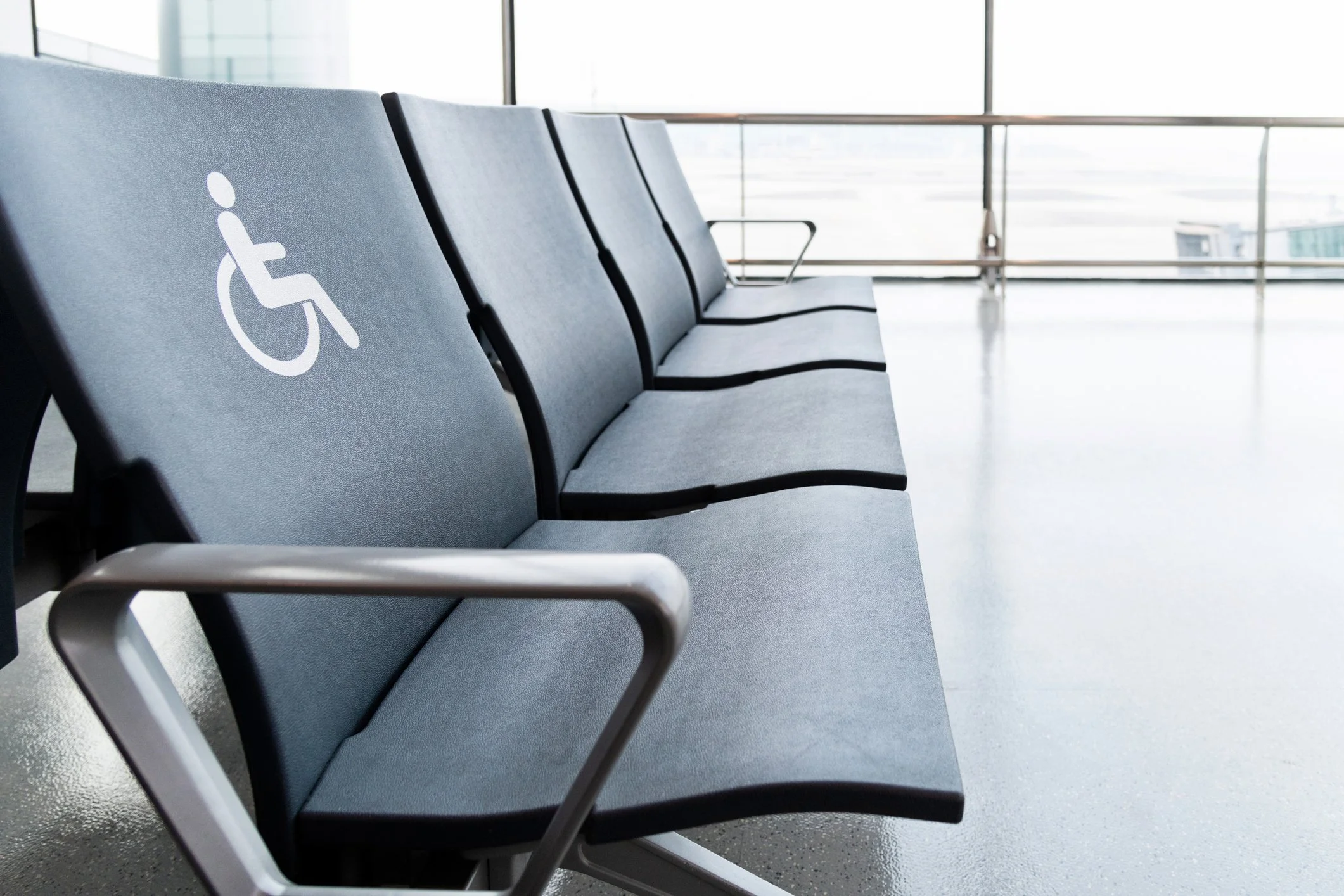 Older gentleman in wheelchair being assisted by a staff member through jet bridge to board plane.
