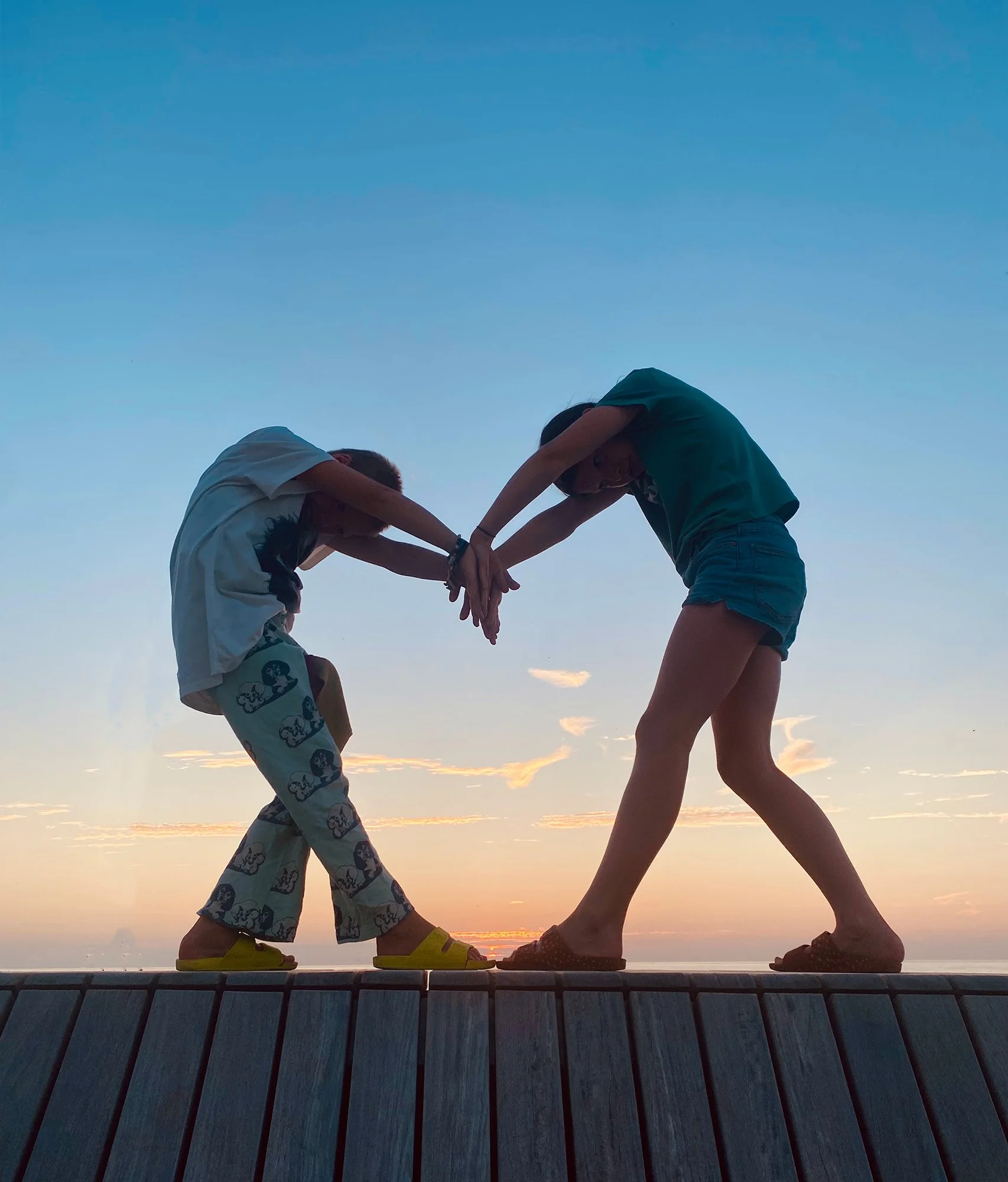 Twee kinderen die elkaar vasthouden en samen bewegen bij zonsondergang als symbool voor verbinding en balans.