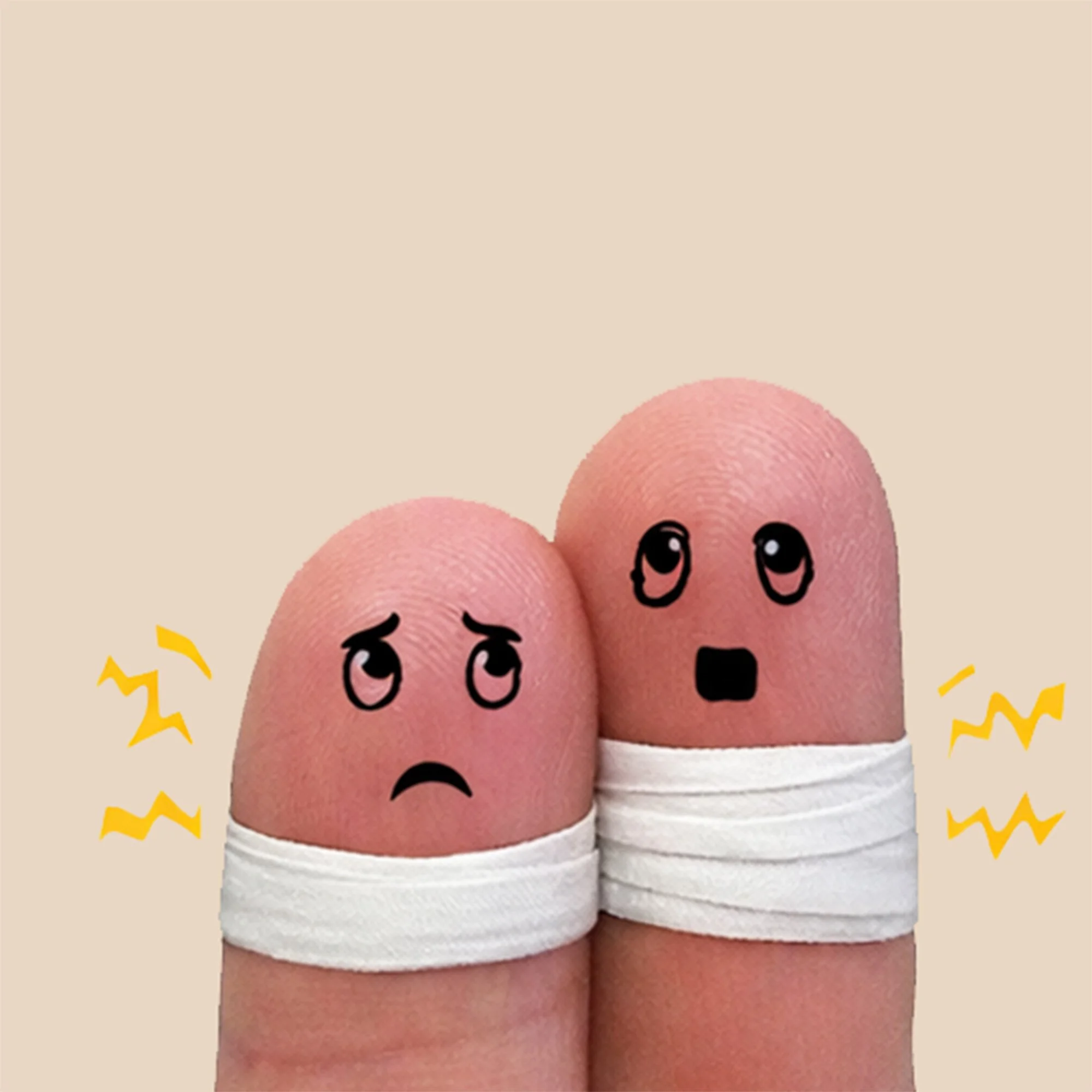 Twee vingers met pleisters en bezorgde gezichtjes als symbool voor fysieke blokkades in het lichaam.