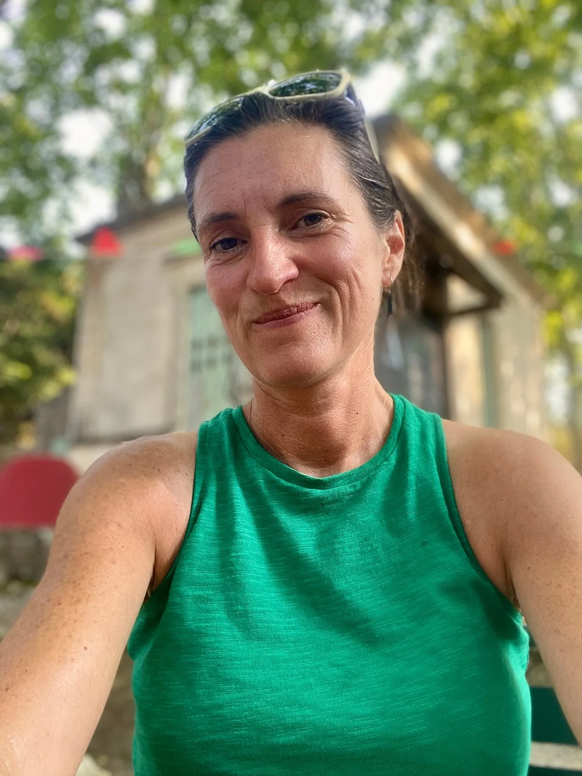 Vrouw die ontspannen in een groene natuurlijke omgeving zit en zacht glimlacht.