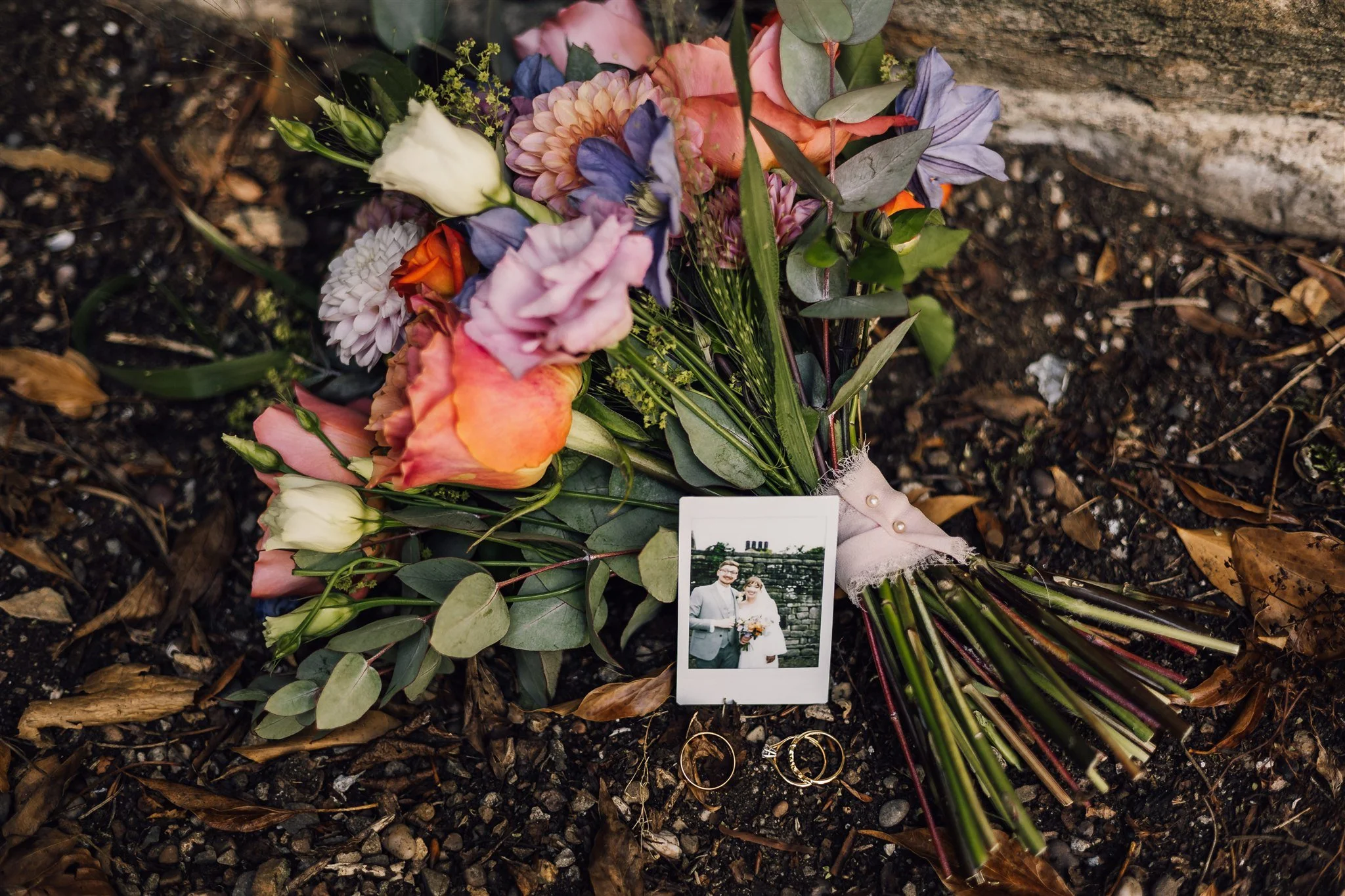 Wedding bouquet with rings and polaroid photo detail at East Riddlesden Hall